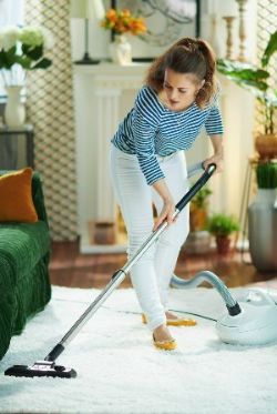 Woman Vacuuming White Fluffy Carpet — Nicholasville, KY — Stewart Air Conditioning & Heating