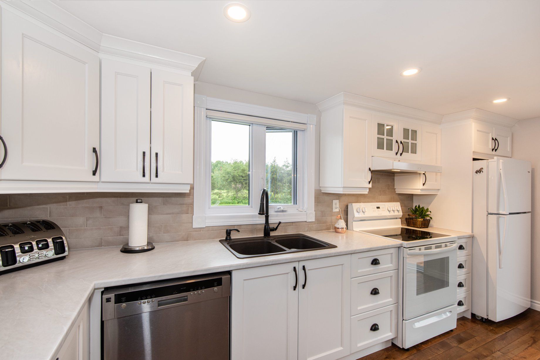 Une cuisine avec des armoires blanches et des appareils électroménagers en acier inoxydable.