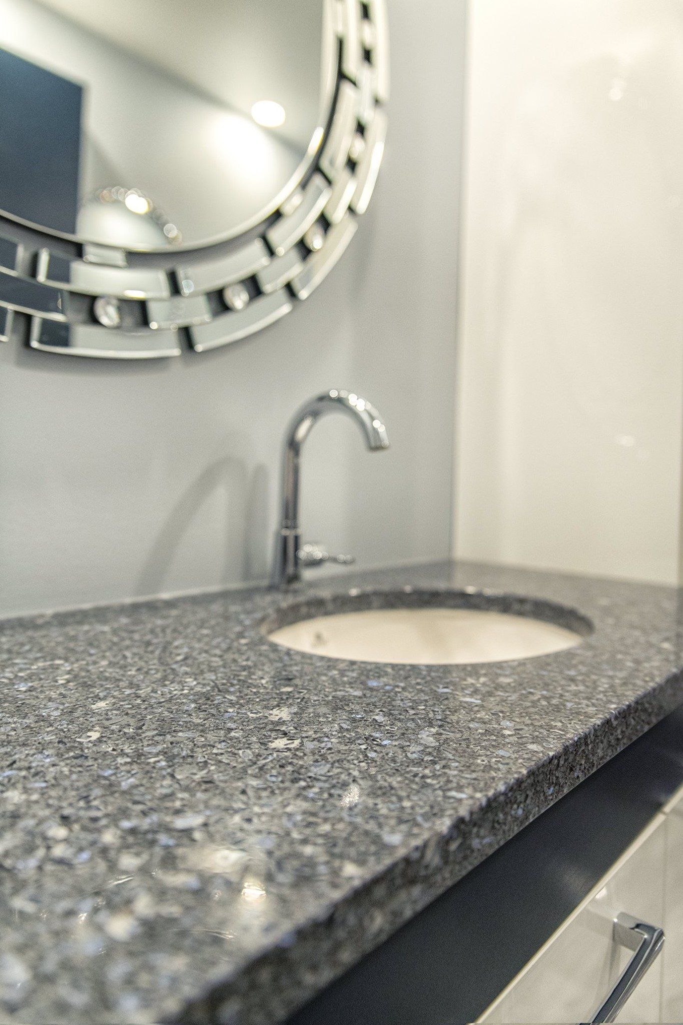 Un lavabo de salle de bain avec un miroir rond au-dessus.