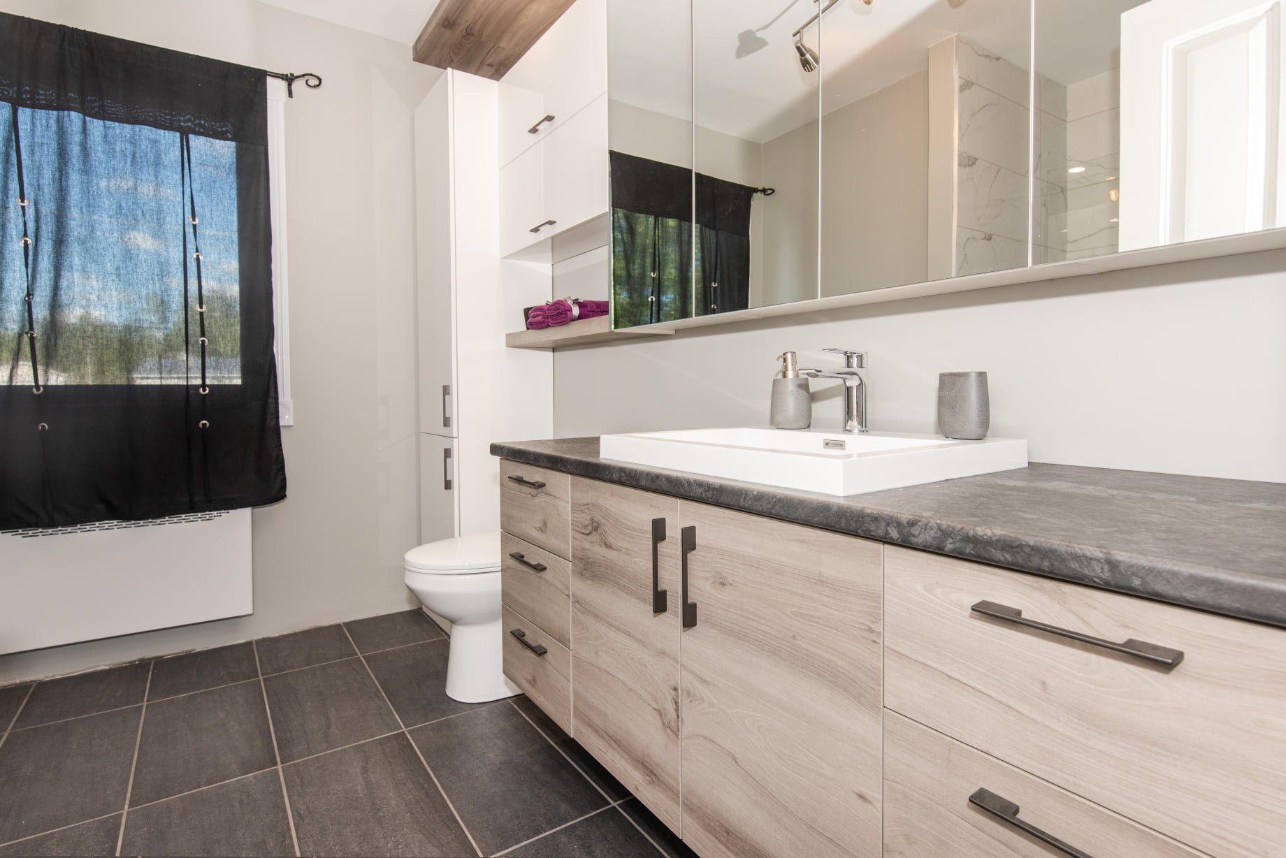 Une salle de bain avec toilettes, lavabo et miroir.