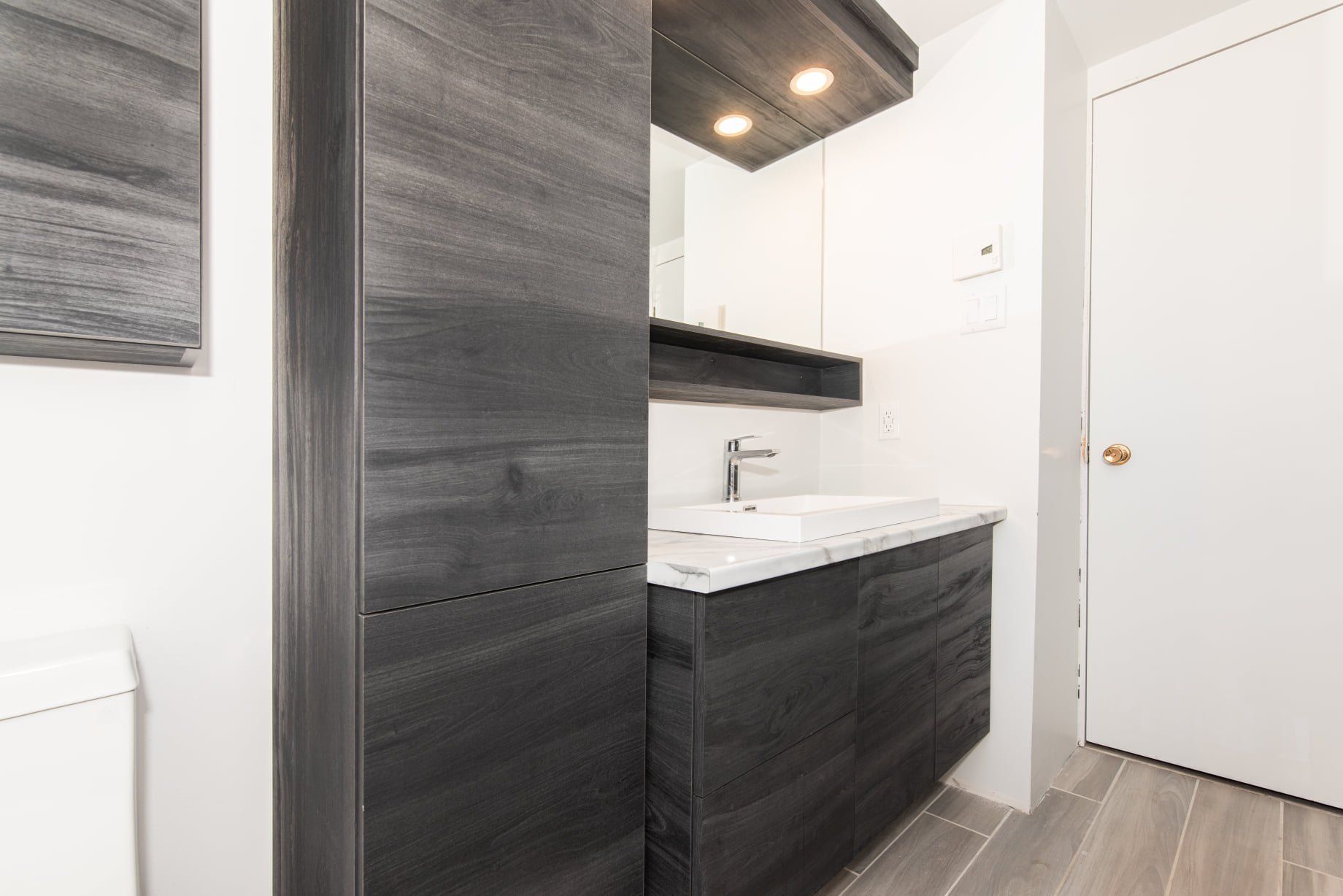 Une salle de bain avec lavabo, miroir et armoires.
