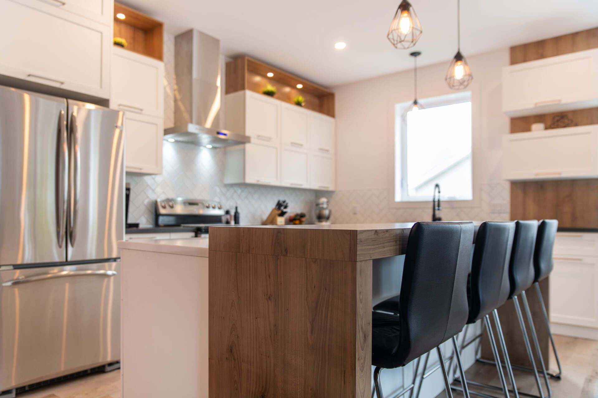 Une cuisine avec des appareils électroménagers en acier inoxydable, des armoires blanches et un grand îlot.