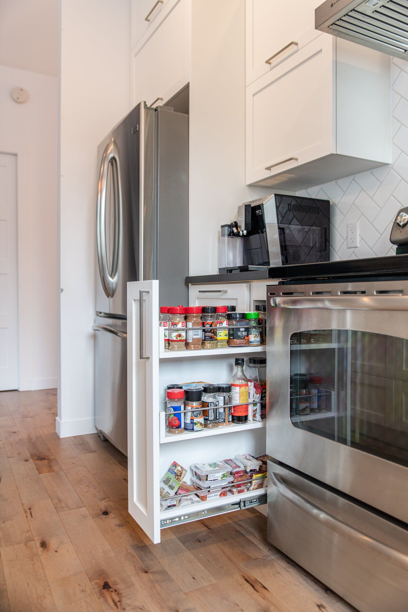 Une cuisine avec un support à épices coulissant à côté d'un réfrigérateur.
