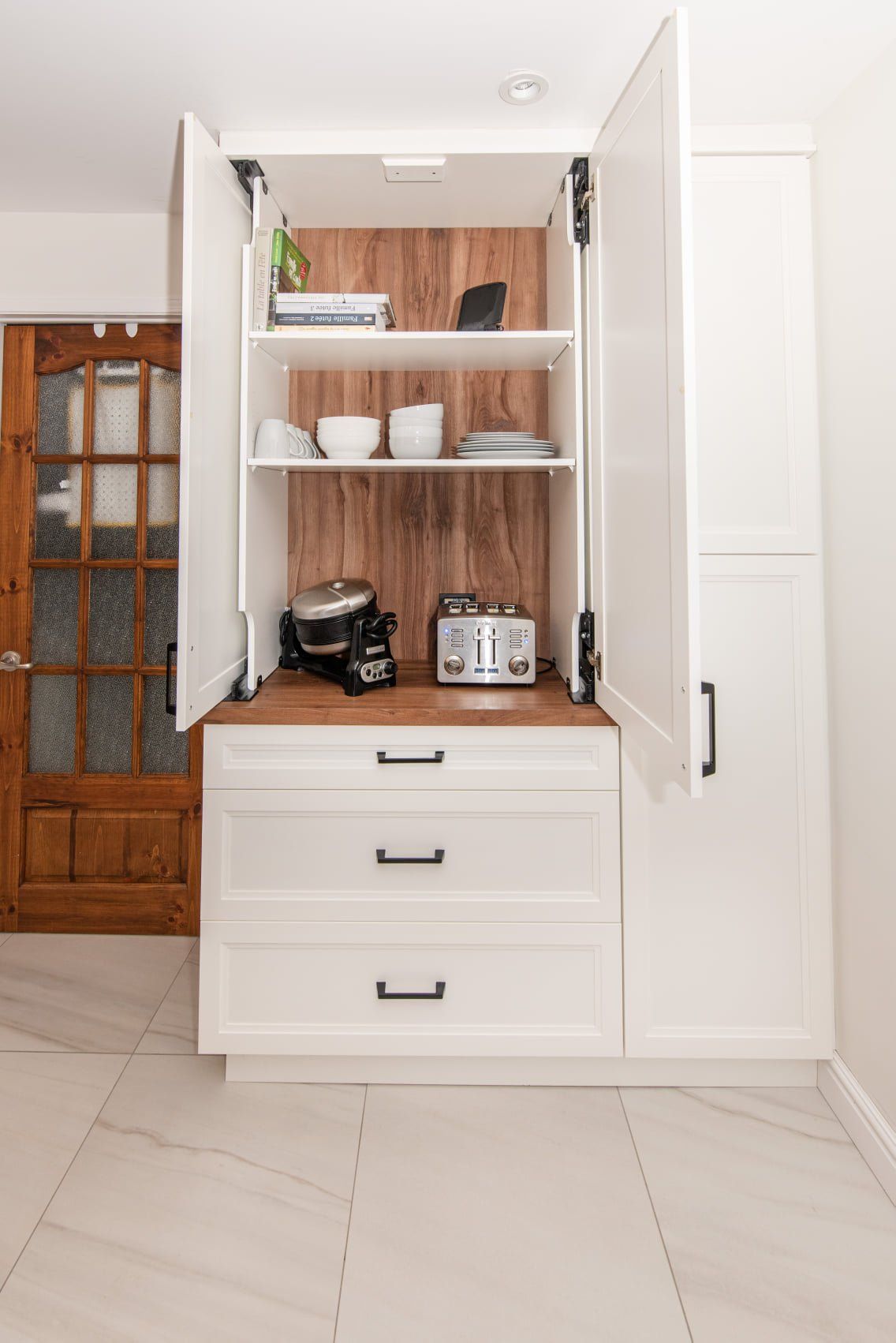 Une cuisine avec des armoires et des tiroirs blancs et un four grille-pain.