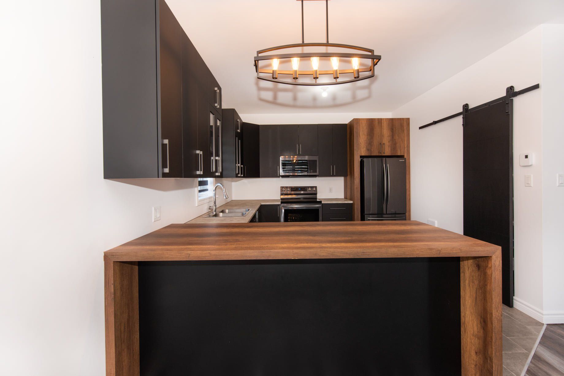 Une cuisine avec des armoires noires et un comptoir en bois