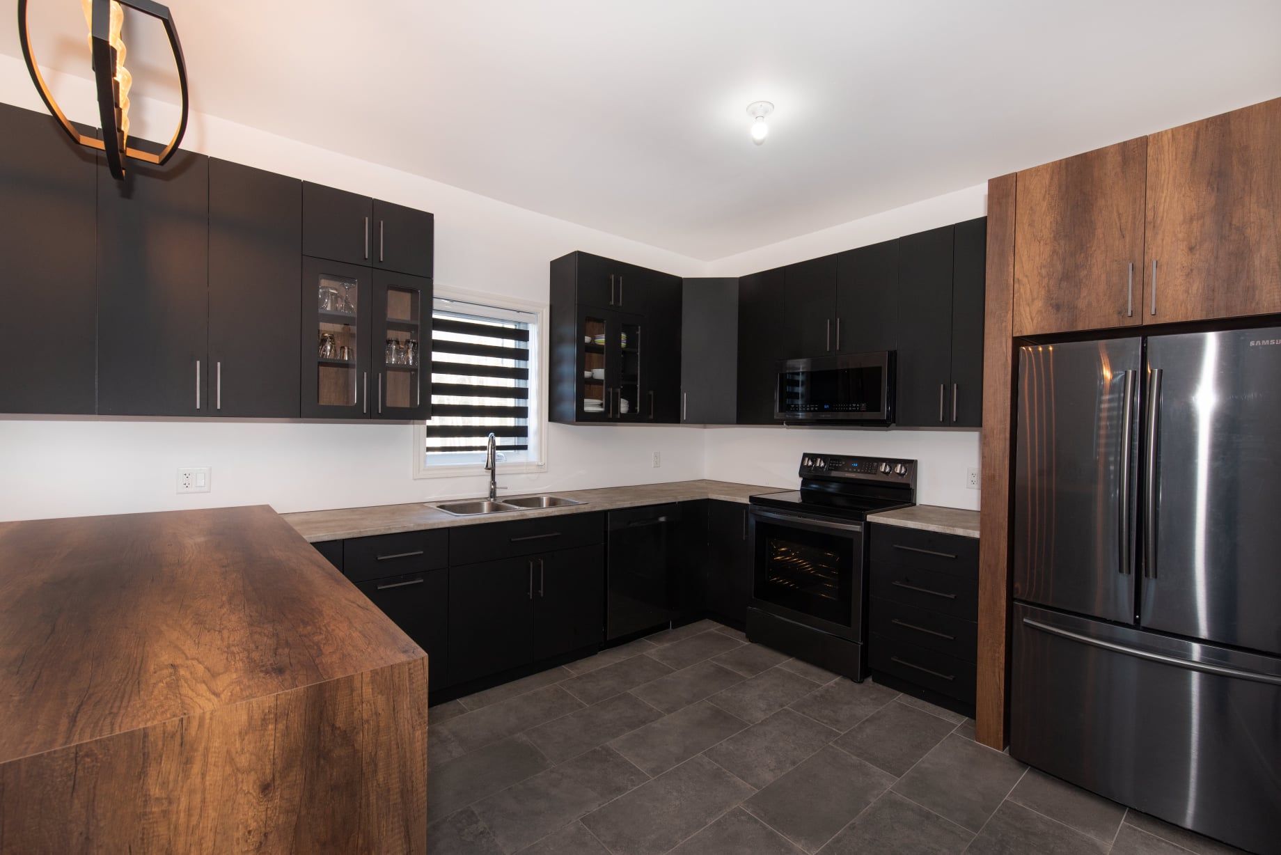 Une cuisine avec des armoires noires et des appareils électroménagers en acier inoxydable