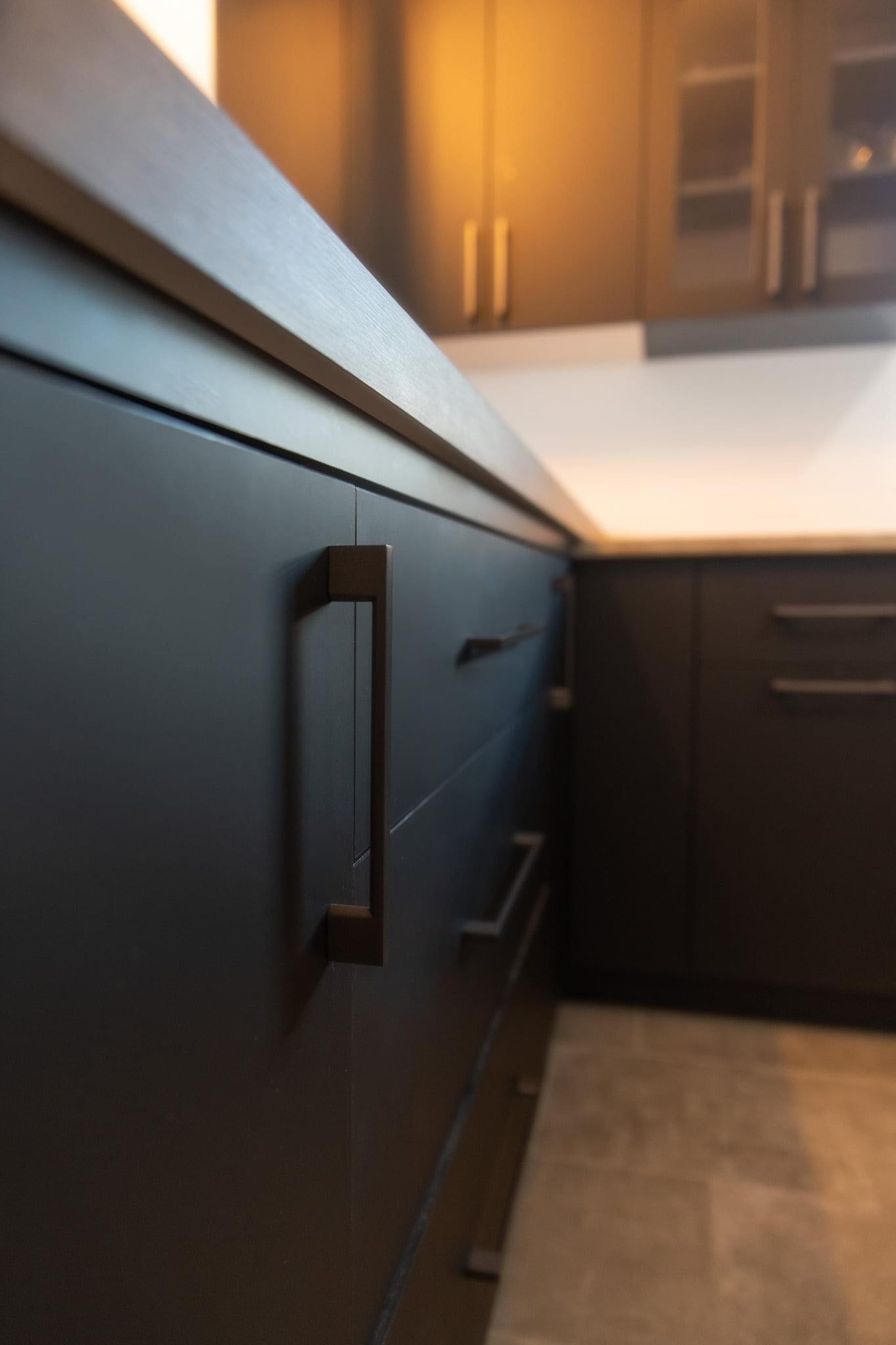 Une cuisine avec des armoires noires et un comptoir blanc