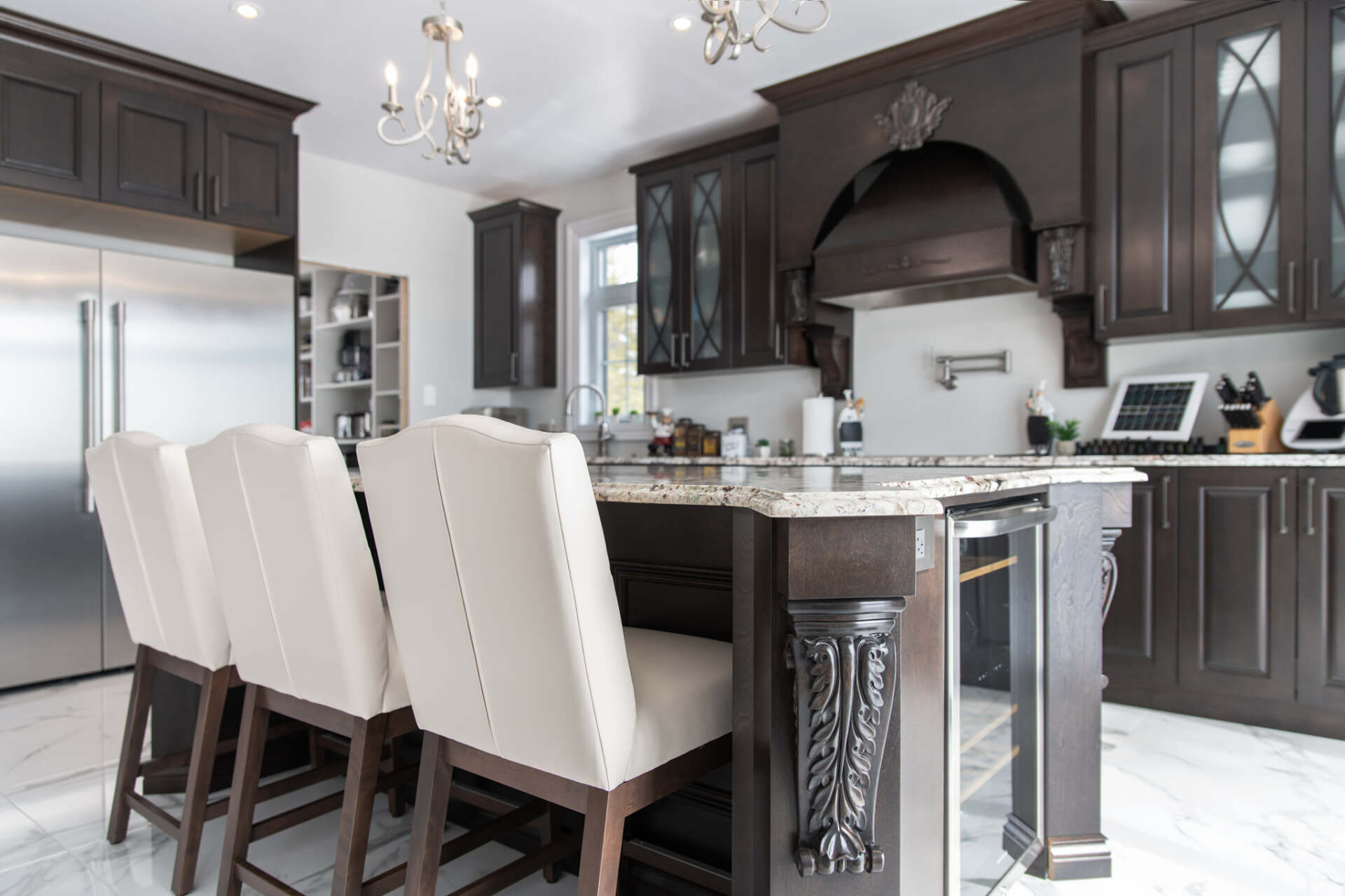 Une cuisine avec des électroménagers en acier inoxydable, des armoires en bois, des comptoirs en granit et un grand îlot.