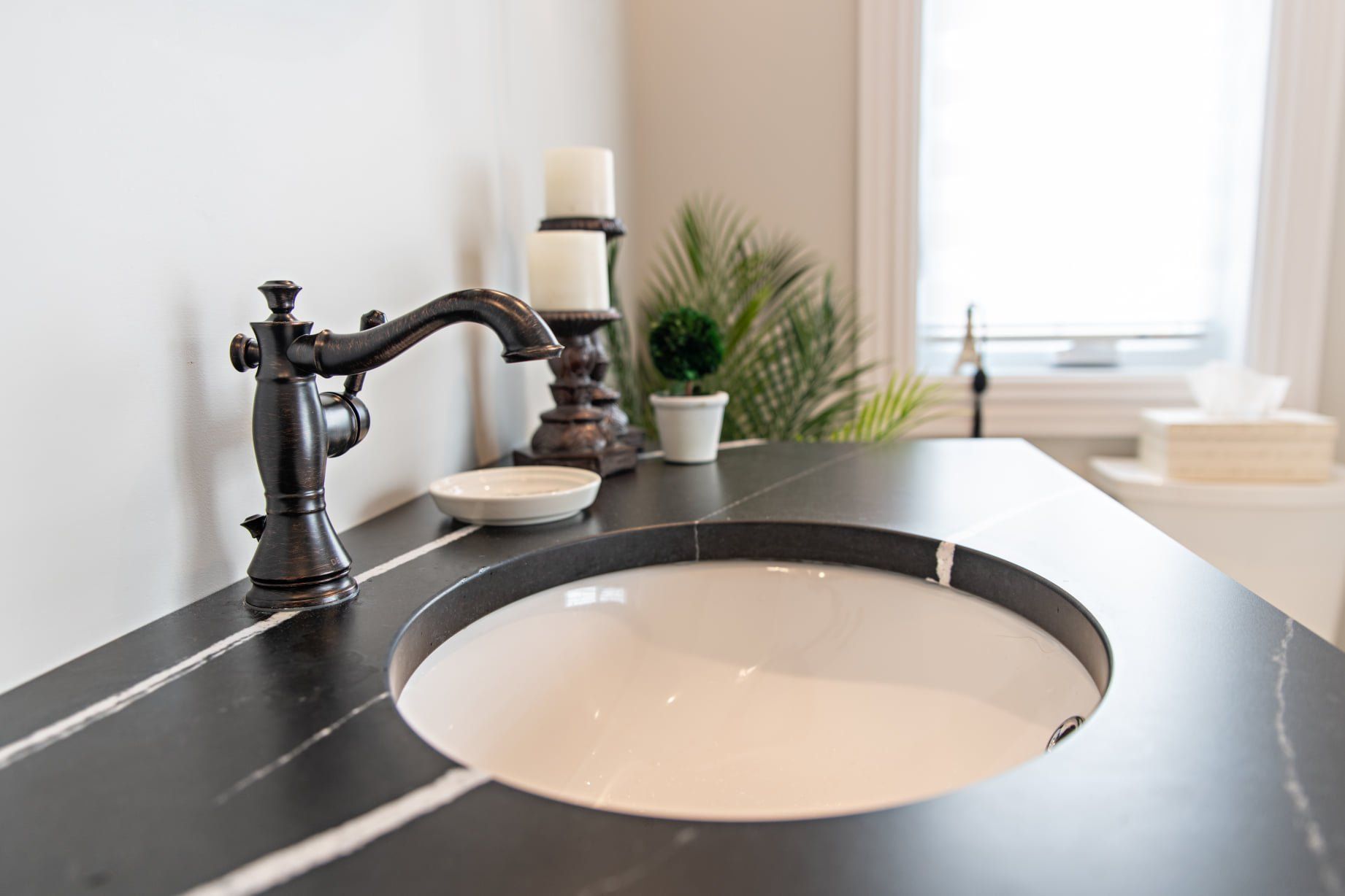 Un lavabo de salle de bain avec un comptoir noir et un robinet noir.