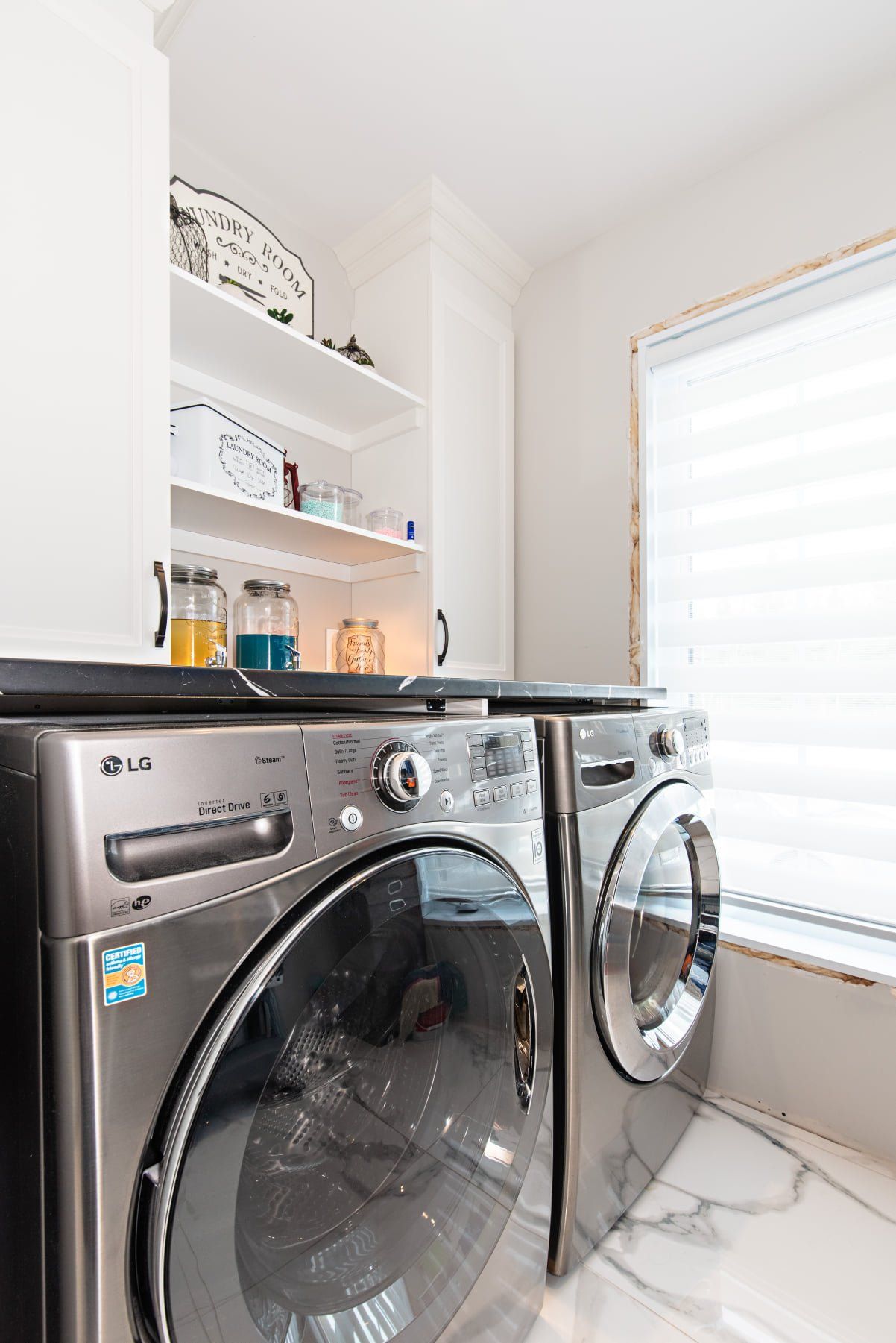 Une laveuse et une sécheuse se trouvent dans une buanderie à côté d'une fenêtre.