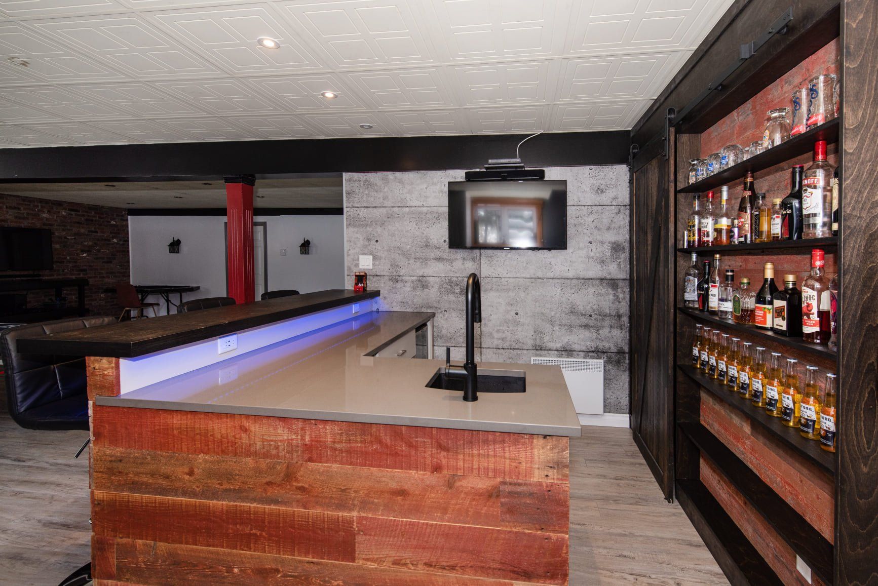 Un bar dans un sous-sol avec des bouteilles d'alcool sur des étagères.