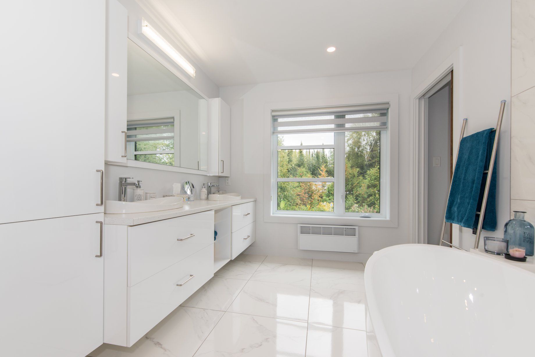 Une salle de bain avec deux lavabos, une baignoire, un miroir et une fenêtre.