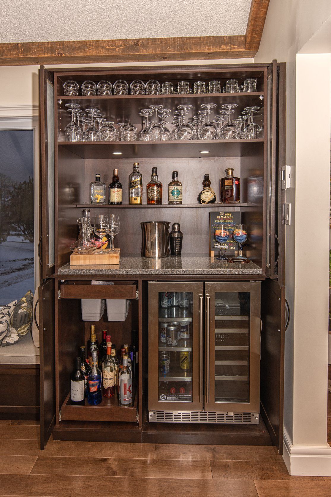 Un bar avec des bouteilles, des verres et un réfrigérateur.