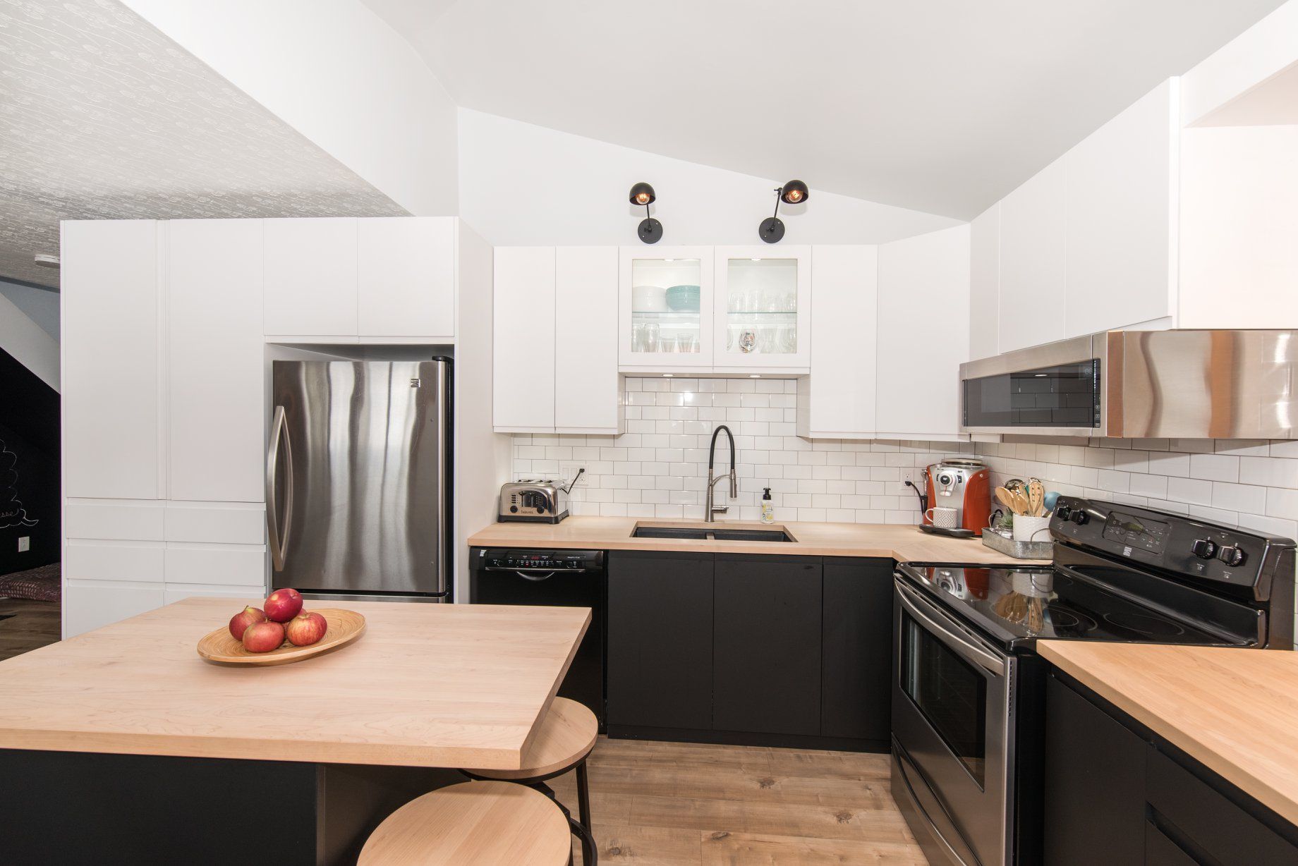 Une cuisine avec des armoires noires, des appareils électroménagers en acier inoxydable et un comptoir en bois.
