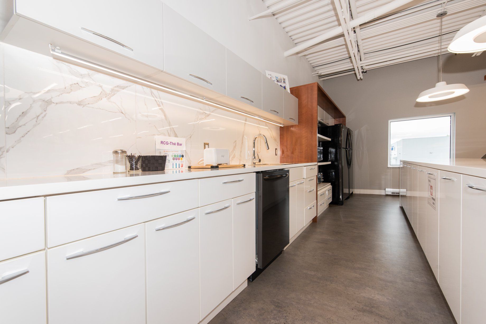 Une cuisine avec des armoires blanches et un lave-vaisselle noir.