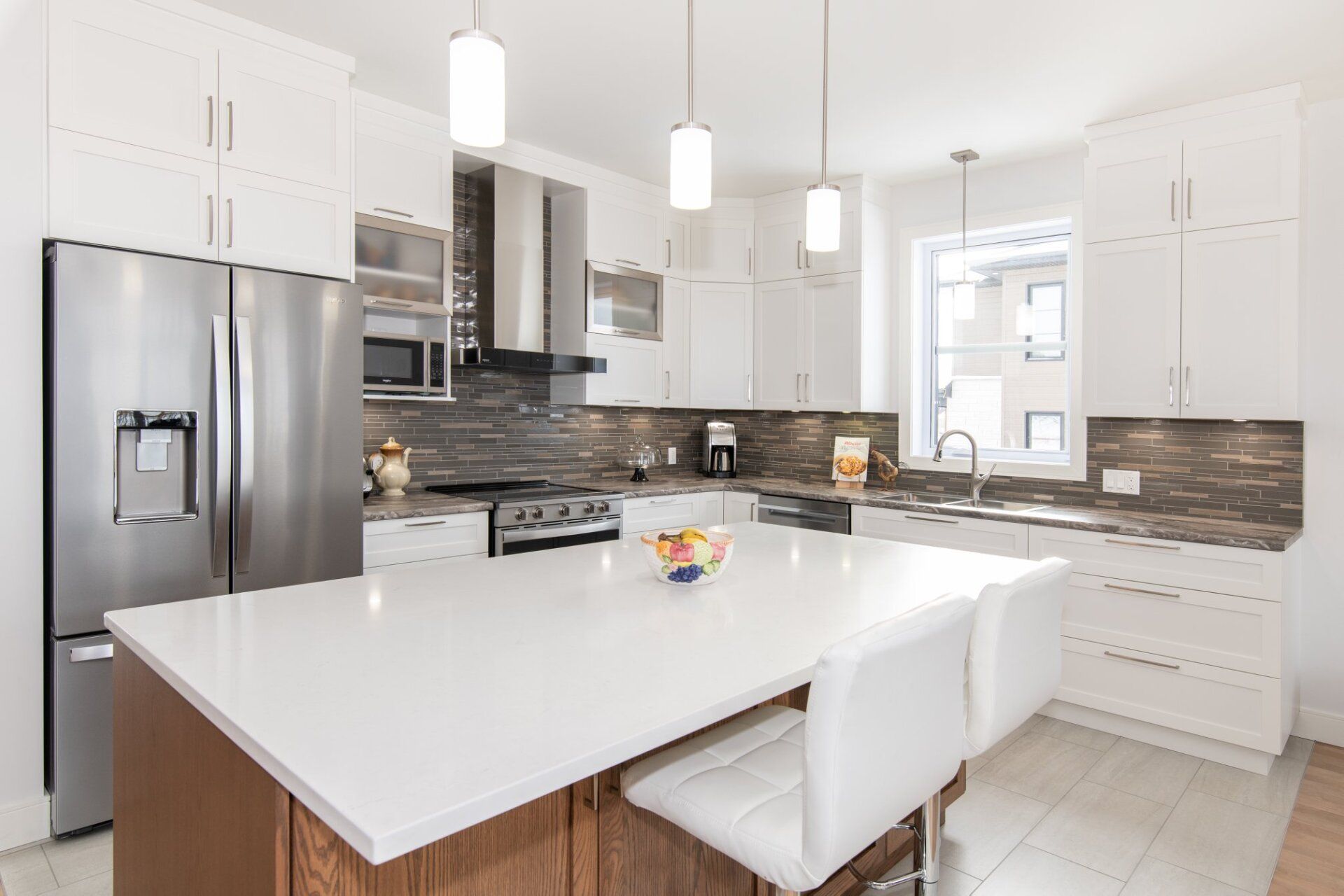 Une cuisine avec des armoires blanches, des appareils électroménagers en acier inoxydable et un grand îlot.