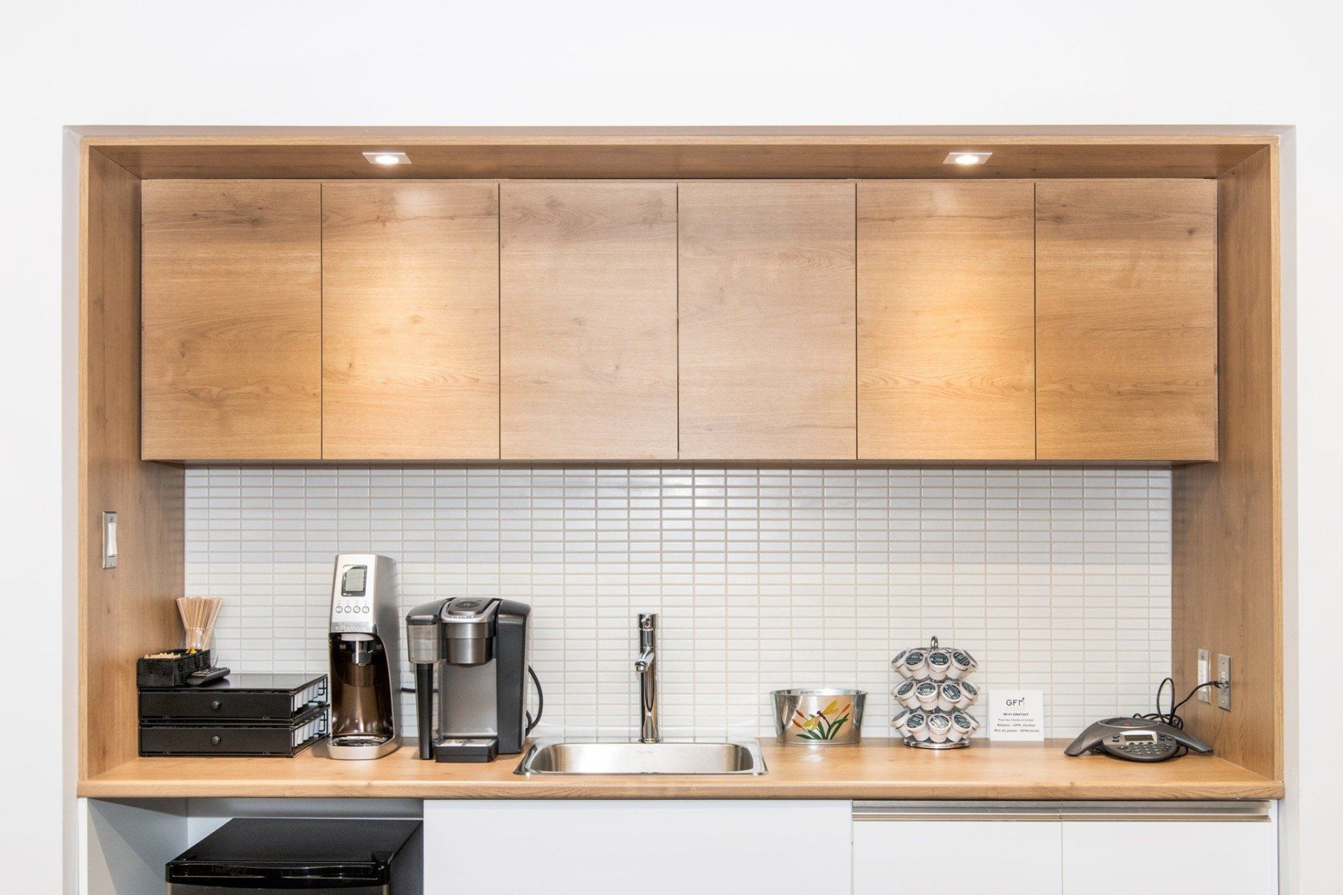 Une cuisine avec des armoires en bois, un évier et une cafetière.