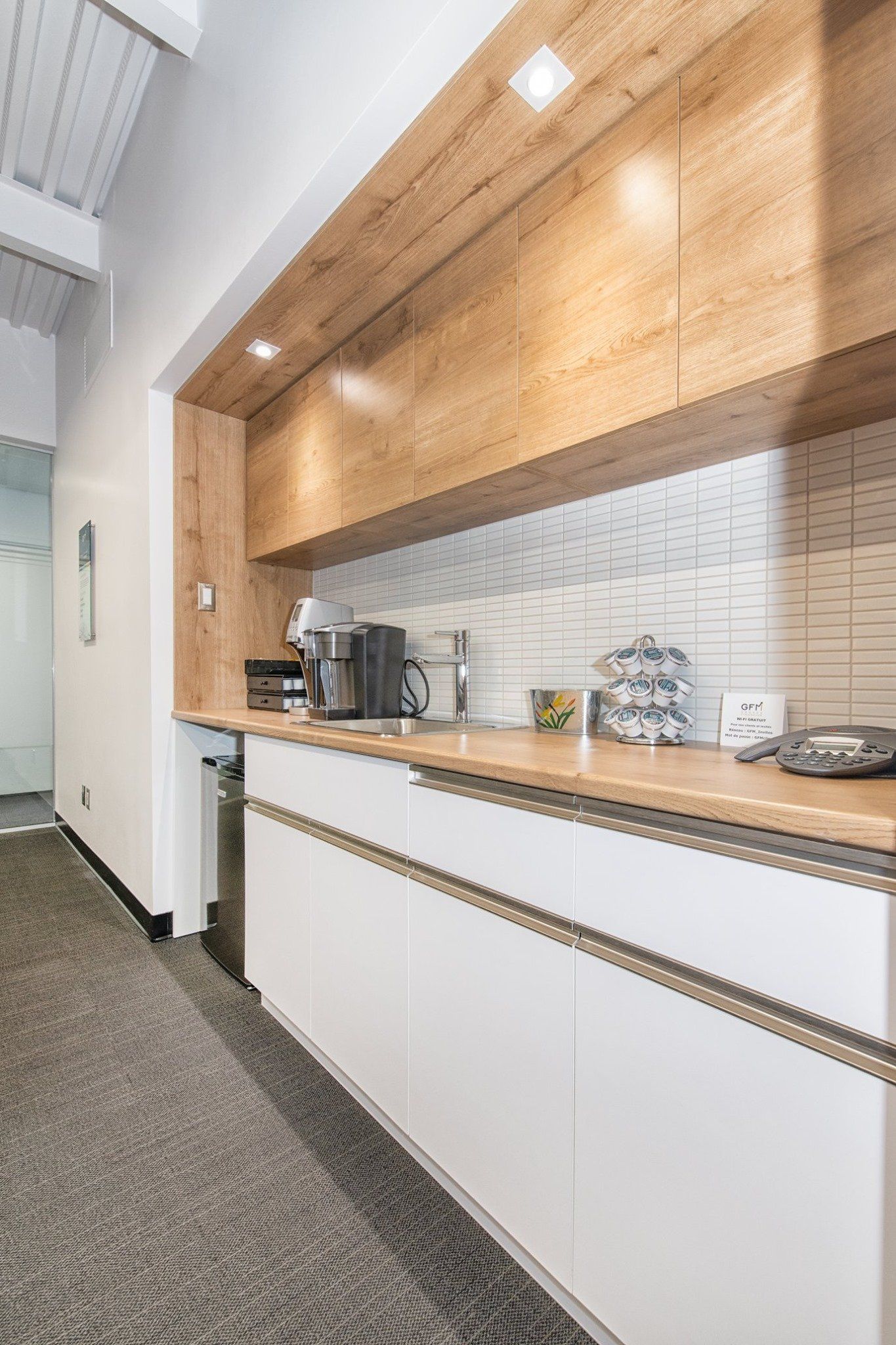 Une cuisine avec des armoires blanches, des armoires en bois et un évier.