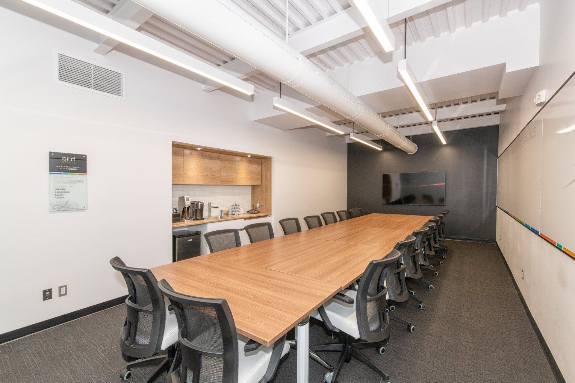 Une salle de conférence avec une longue table en bois et des chaises.