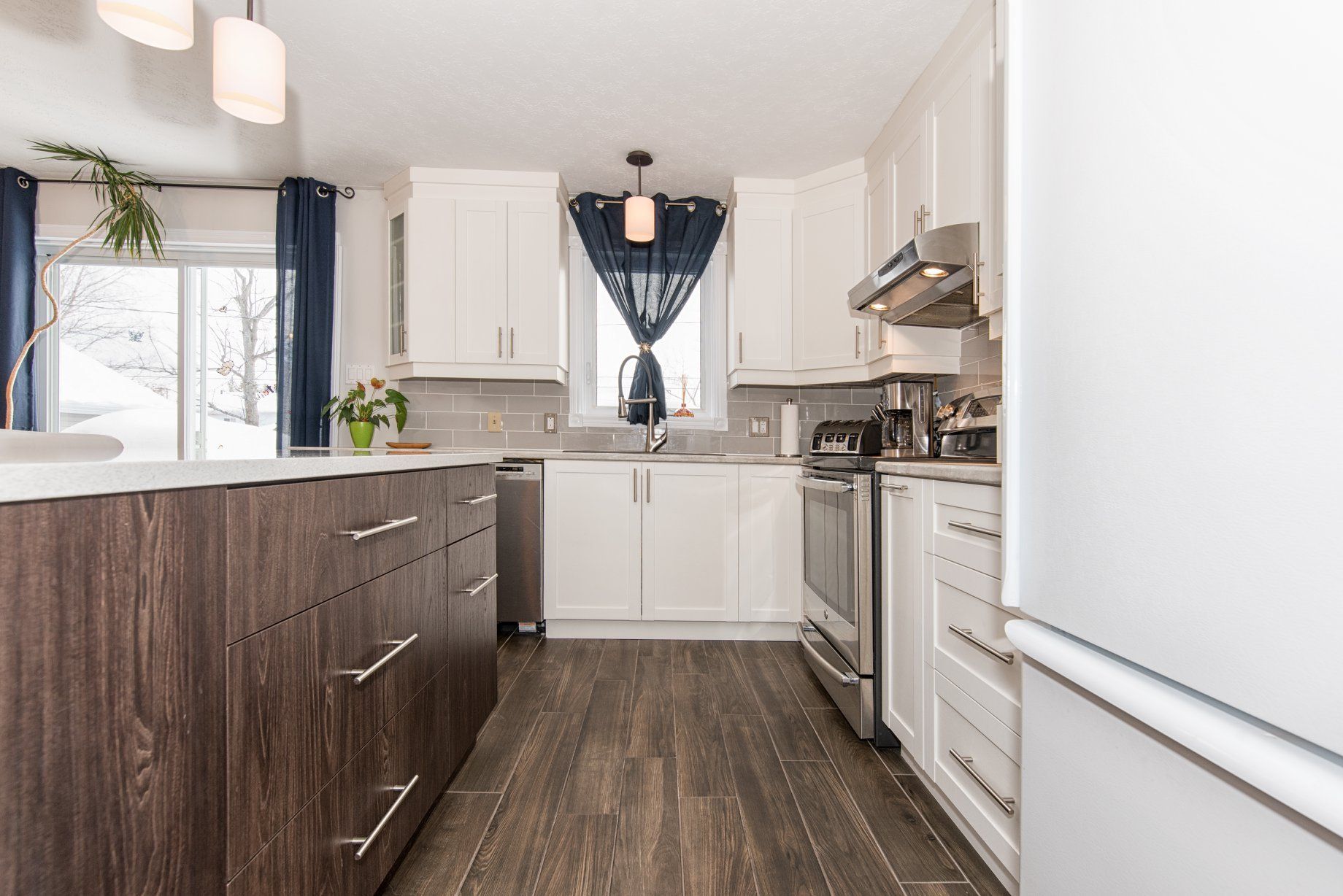 Une cuisine avec des armoires blanches, des appareils en acier inoxydable et des planchers en bois.