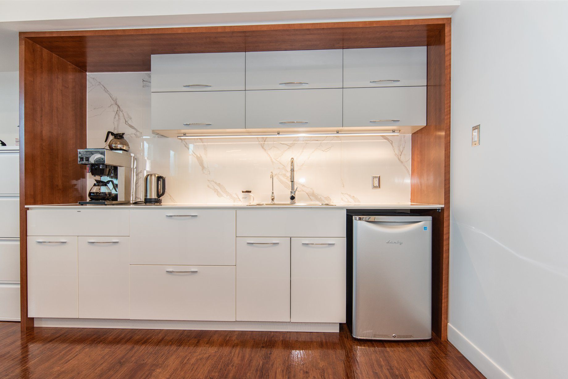 Une cuisine avec des armoires blanches et un réfrigérateur en acier inoxydable