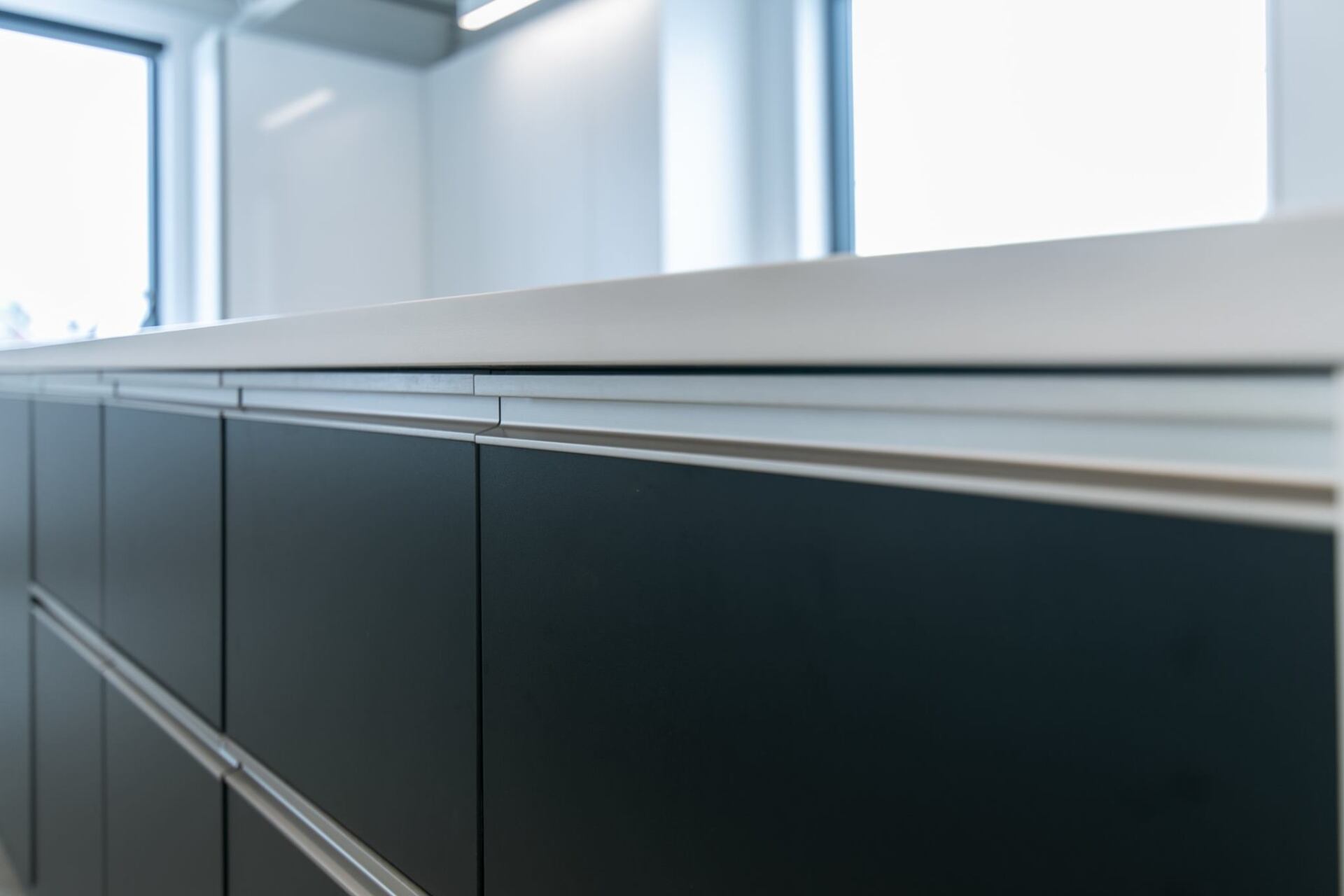 Une cuisine avec des armoires noires et un comptoir blanc.