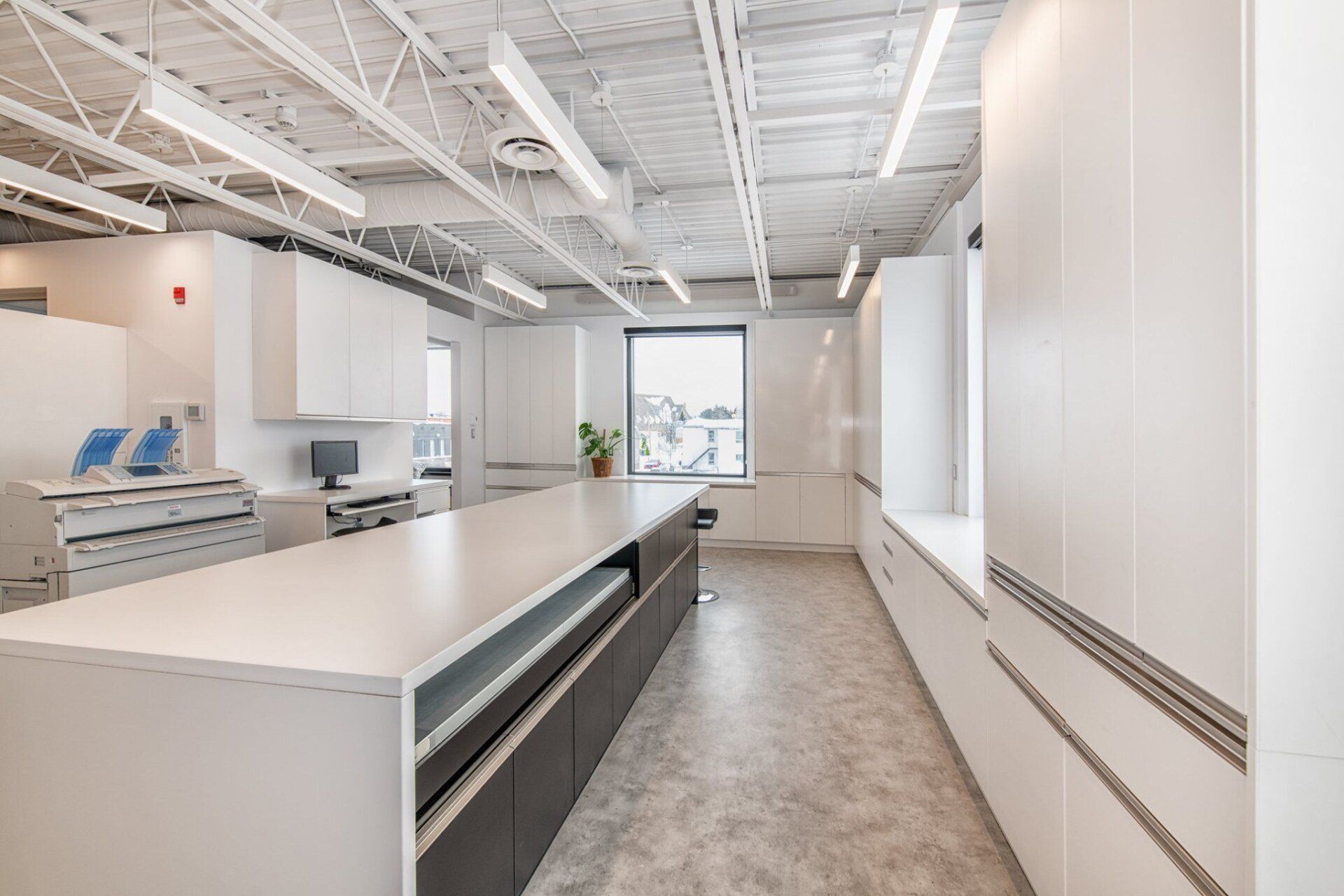 Une longue pièce avec des armoires blanches et un grand comptoir.