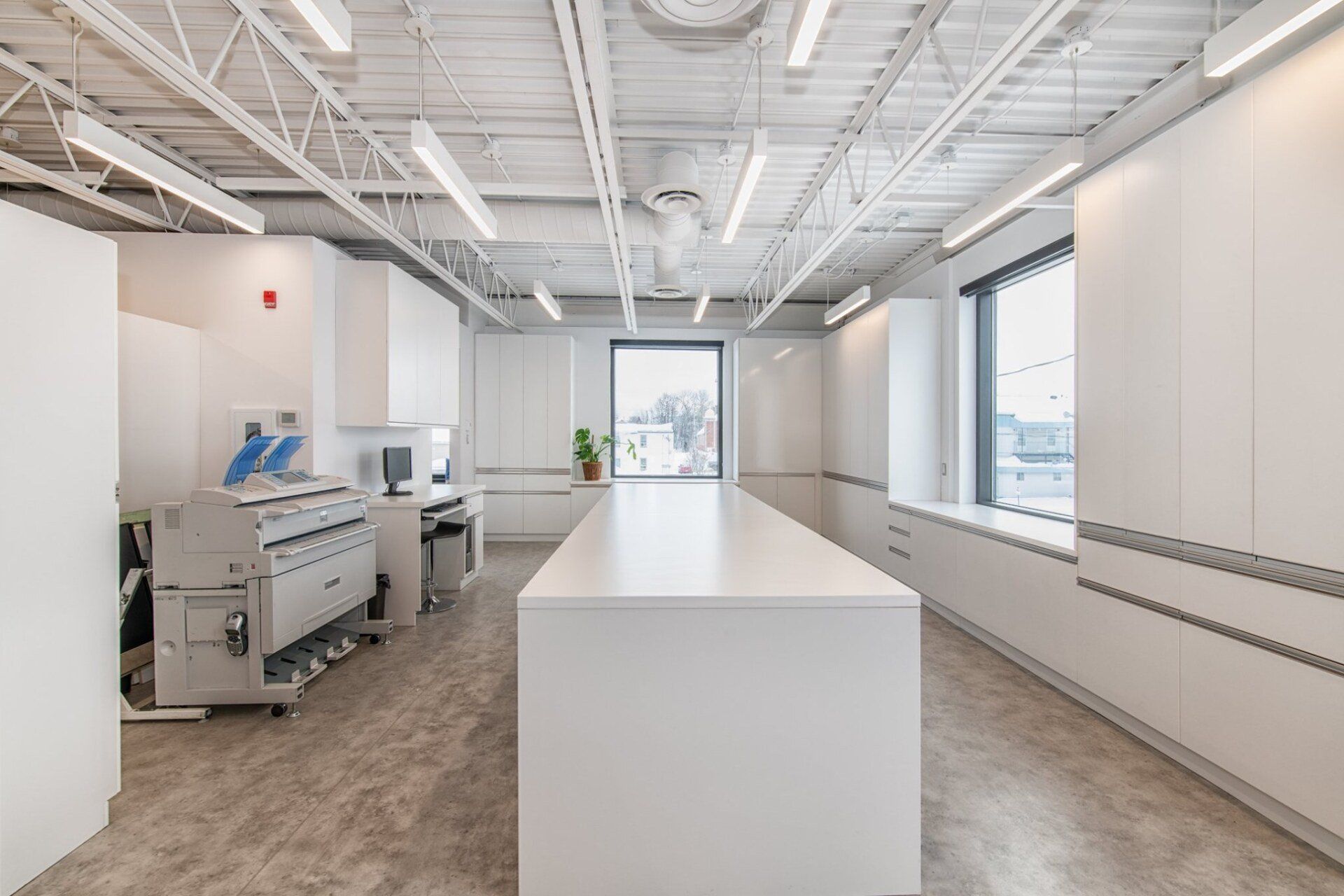 Une grande pièce avec une longue table blanche et une imprimante.