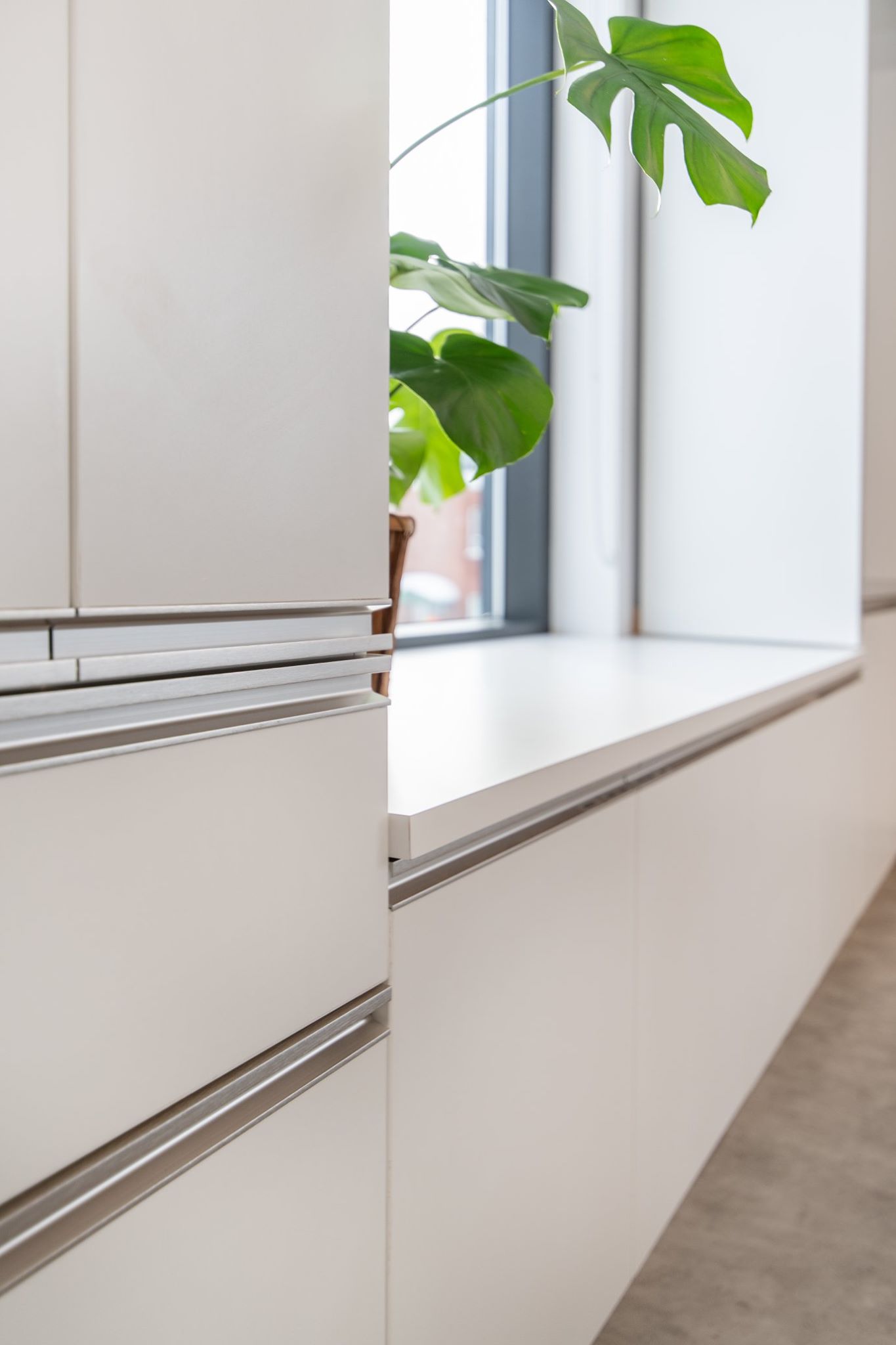 Une plante est assise sur un rebord de fenêtre dans une cuisine.