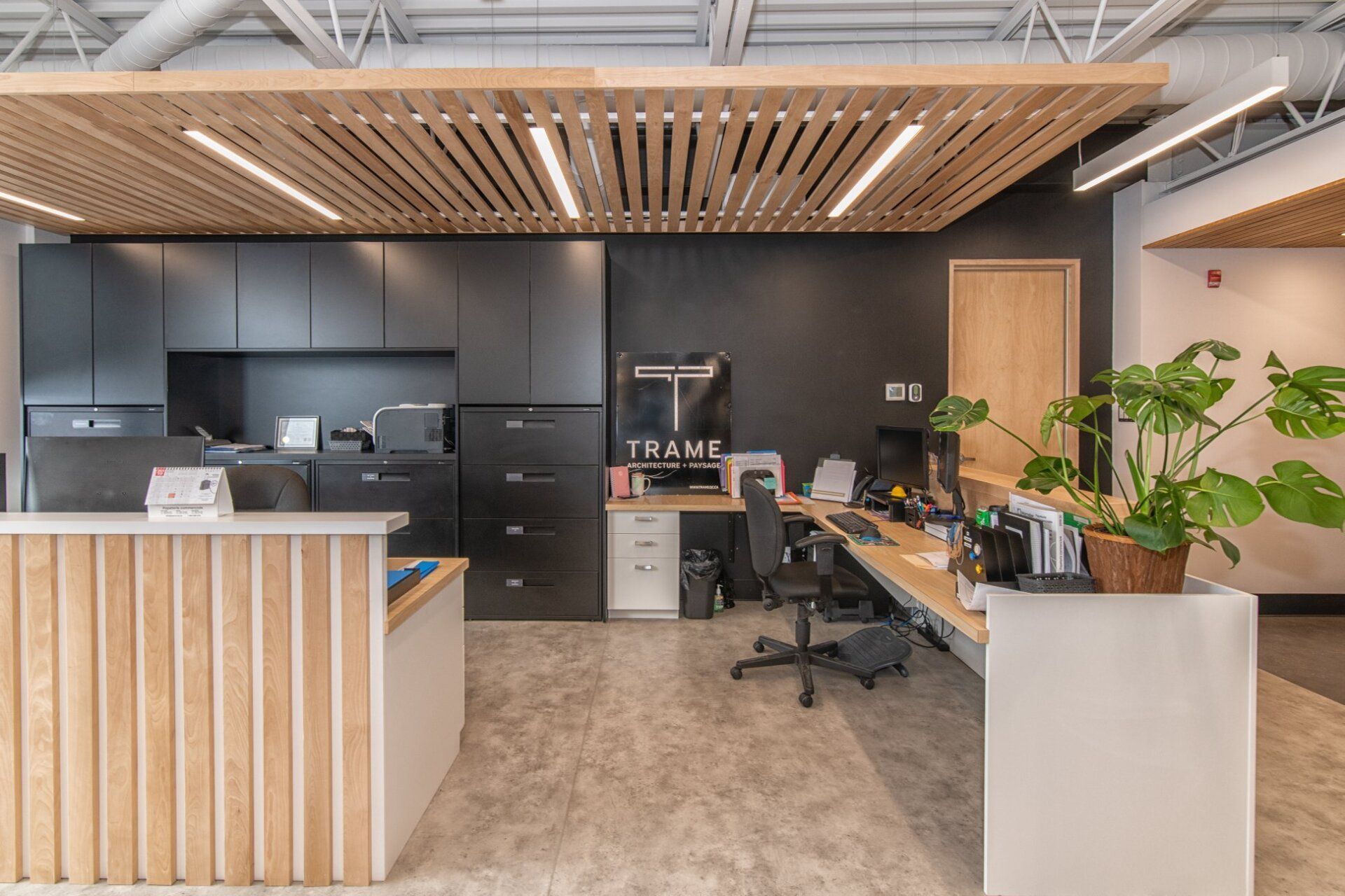 Un espace d'accueil dans un bureau avec un plafond en bois et un bureau.