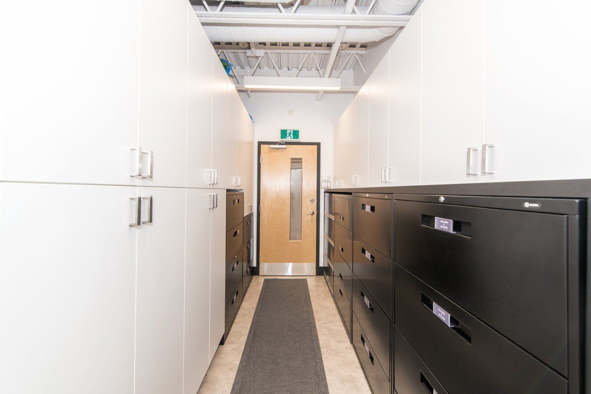 Un couloir avec beaucoup d'armoires et de tiroirs et une porte.
