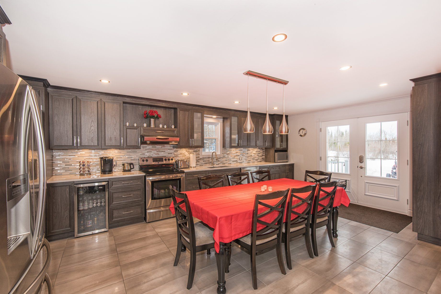 Une cuisine avec une table à manger et des chaises et une nappe rouge.