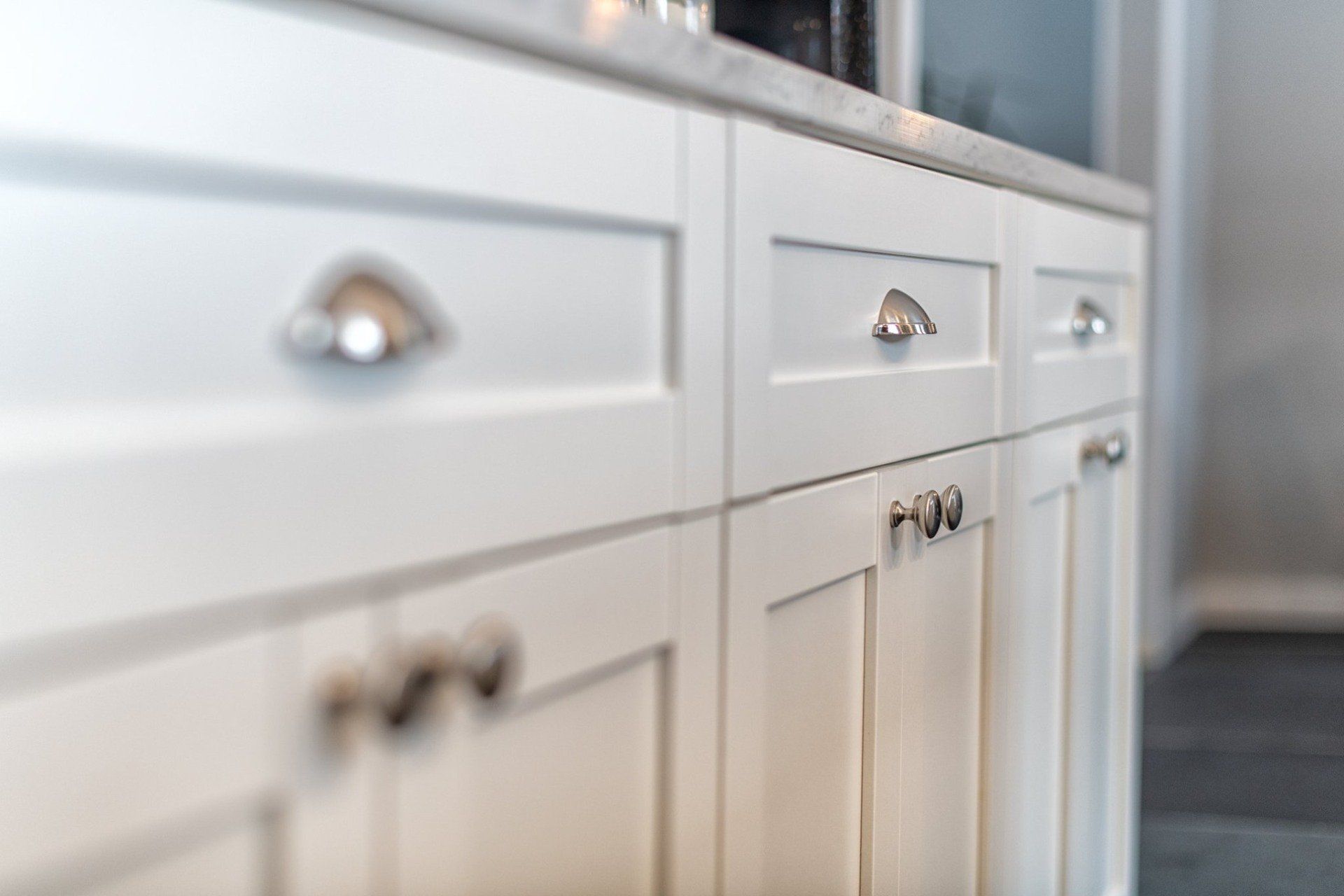 Une cuisine avec des armoires et des tiroirs blancs et un comptoir en marbre.