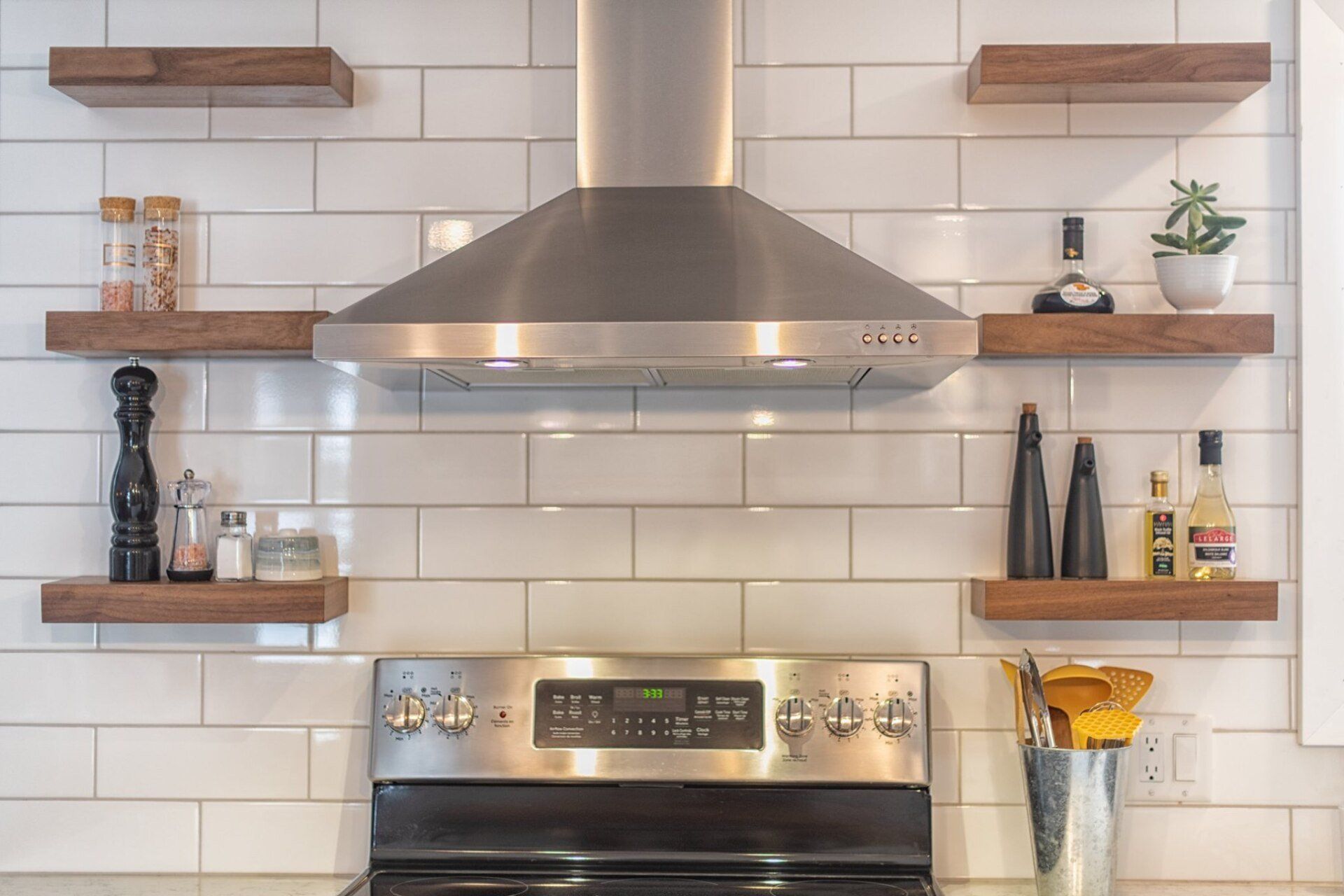 Une cuisine avec une cuisinière et une hotte au-dessus.