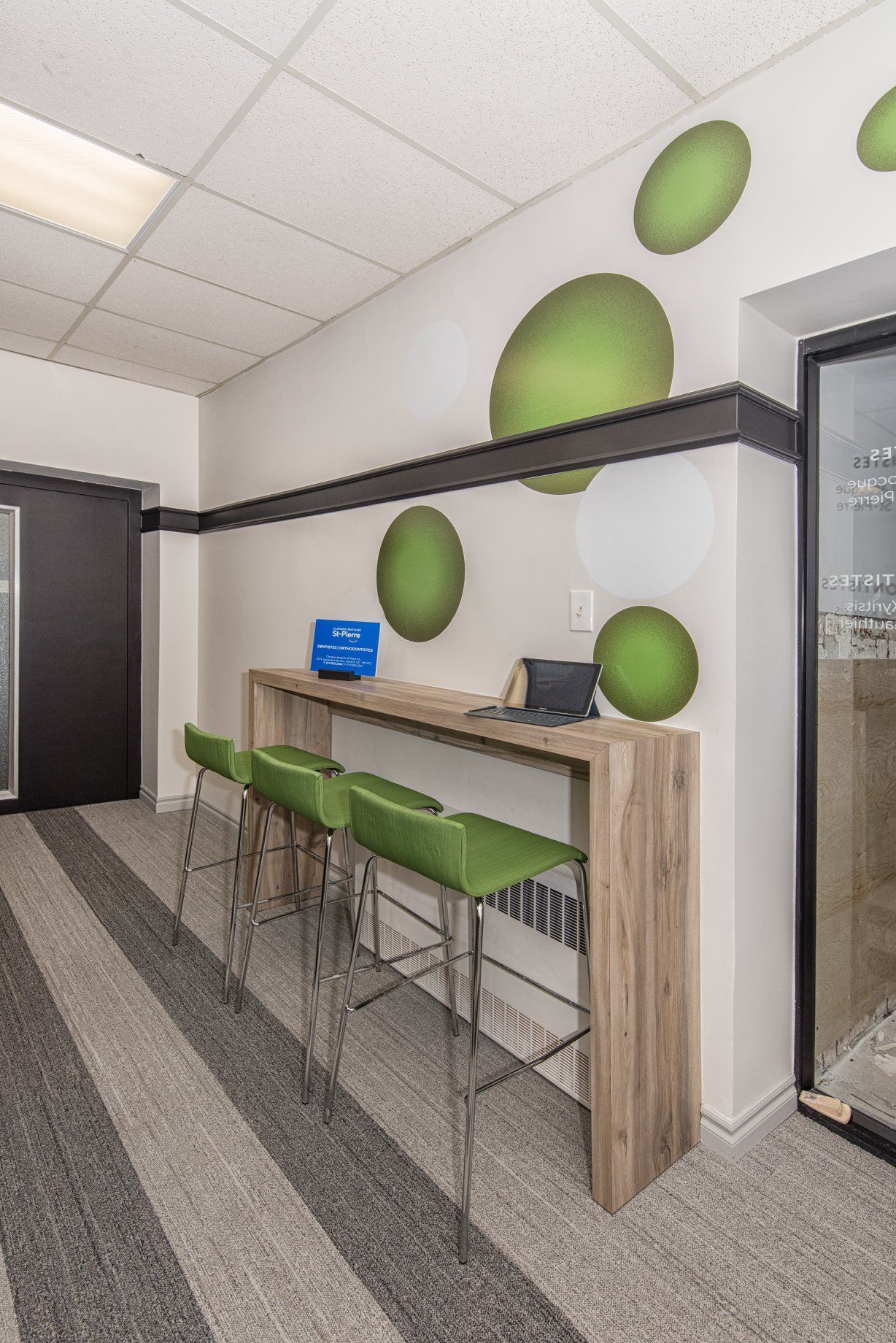 Un couloir avec une longue table en bois et des chaises vertes.
