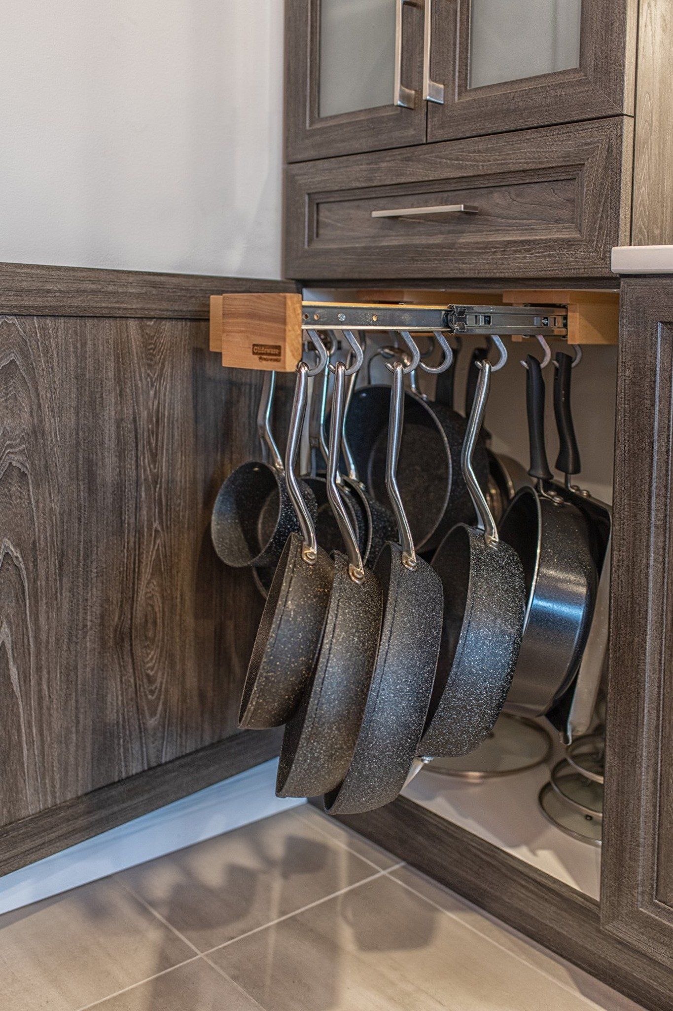 Un tas de casseroles et de poêles suspendues à un support dans une cuisine.