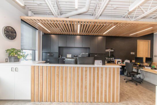 Un espace de réception dans un bureau avec un comptoir en bois et une horloge au mur.