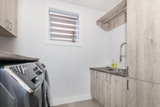 Une buanderie avec laveuse, sécheuse et un évier.