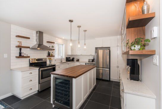 Une cuisine avec des armoires blanches et des appareils électroménagers en acier inoxydable