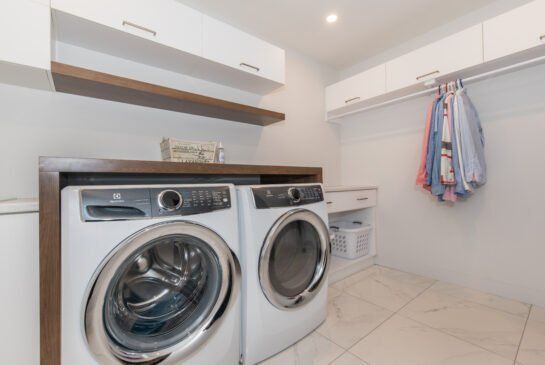 Une buanderie avec une laveuse, une sécheuse et des vêtements accrochés au mur.