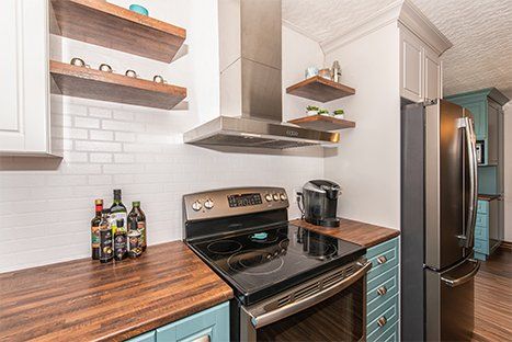 Une cuisine avec une cuisinière, un four, un réfrigérateur et des étagères.