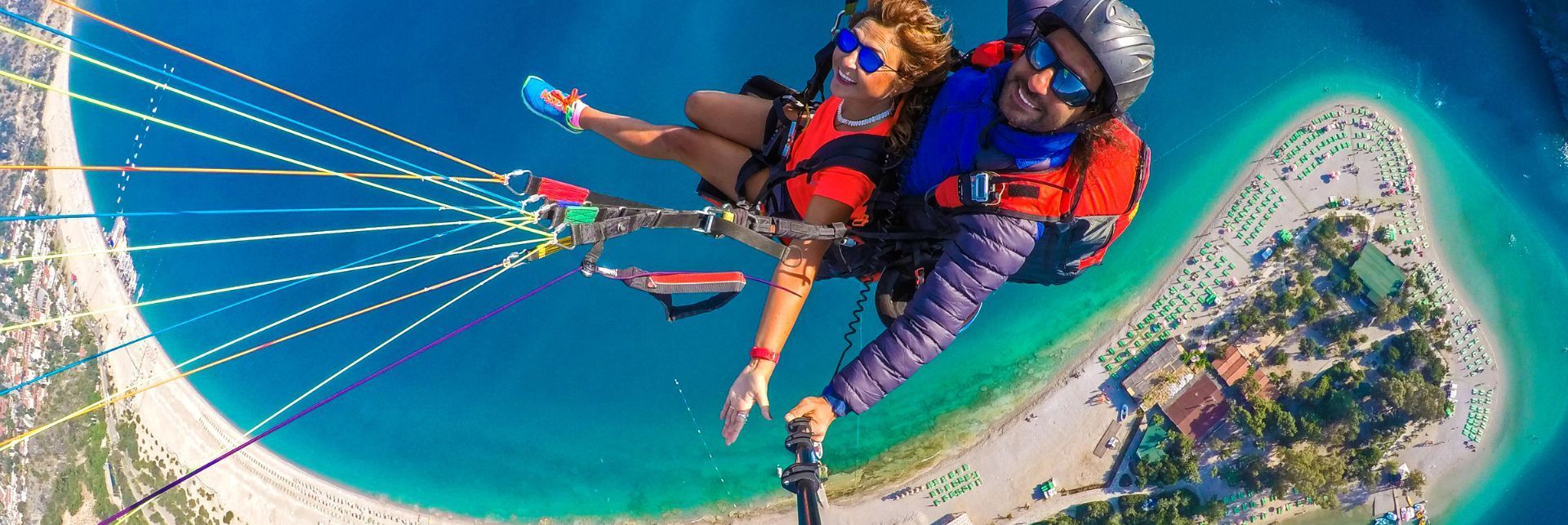 A man and a woman are parasailing over a body of water.