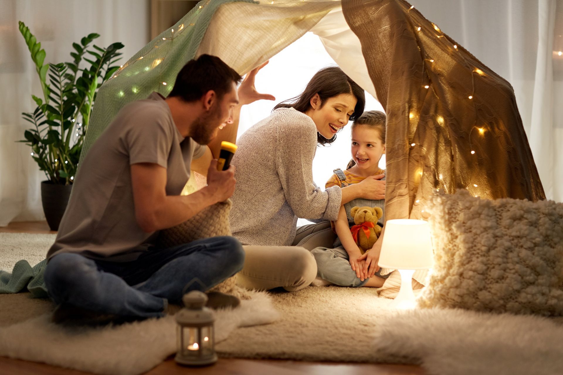 A family is sitting in a tent in a living room.