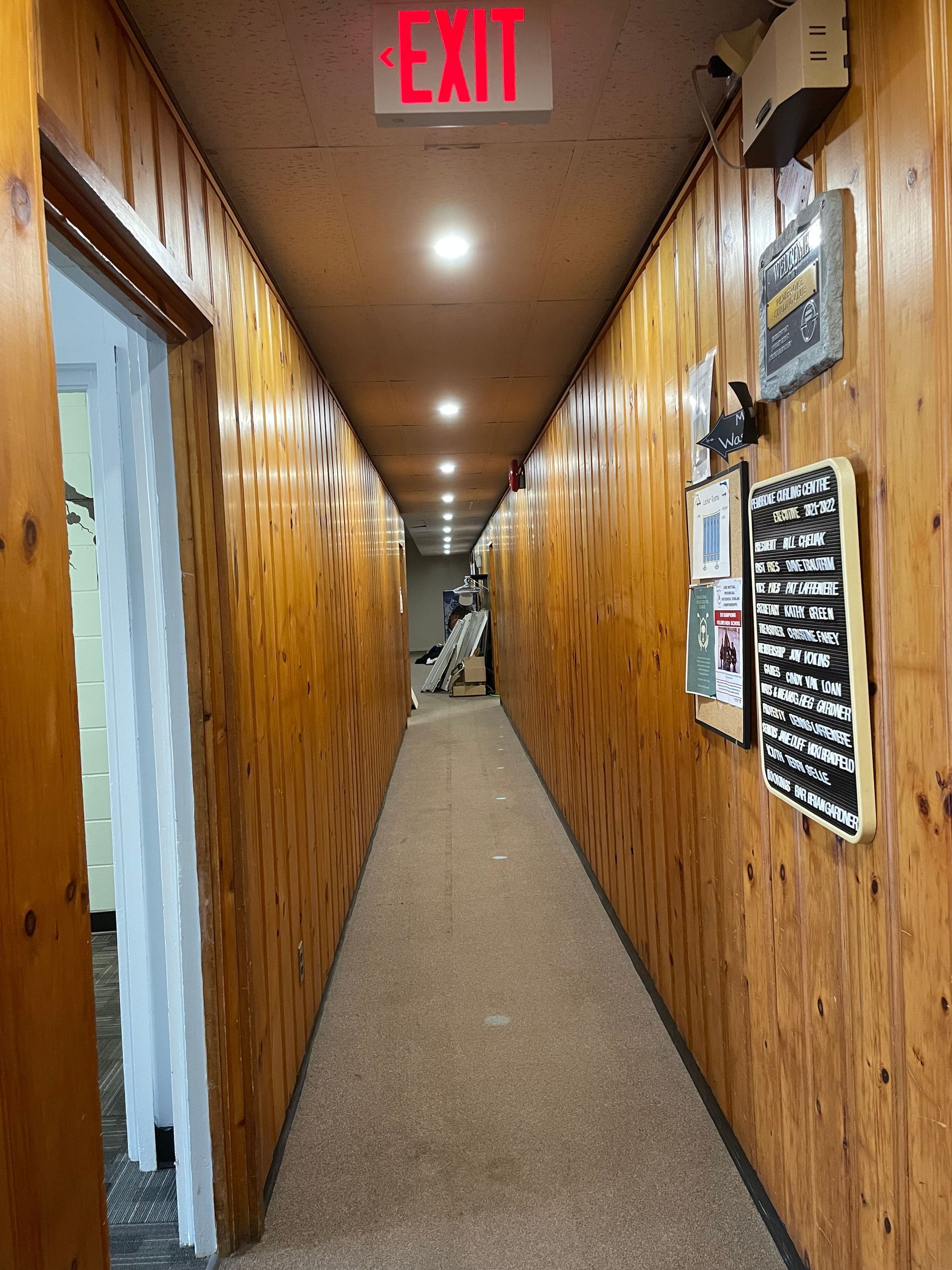 A long hallway with a red exit sign on the ceiling