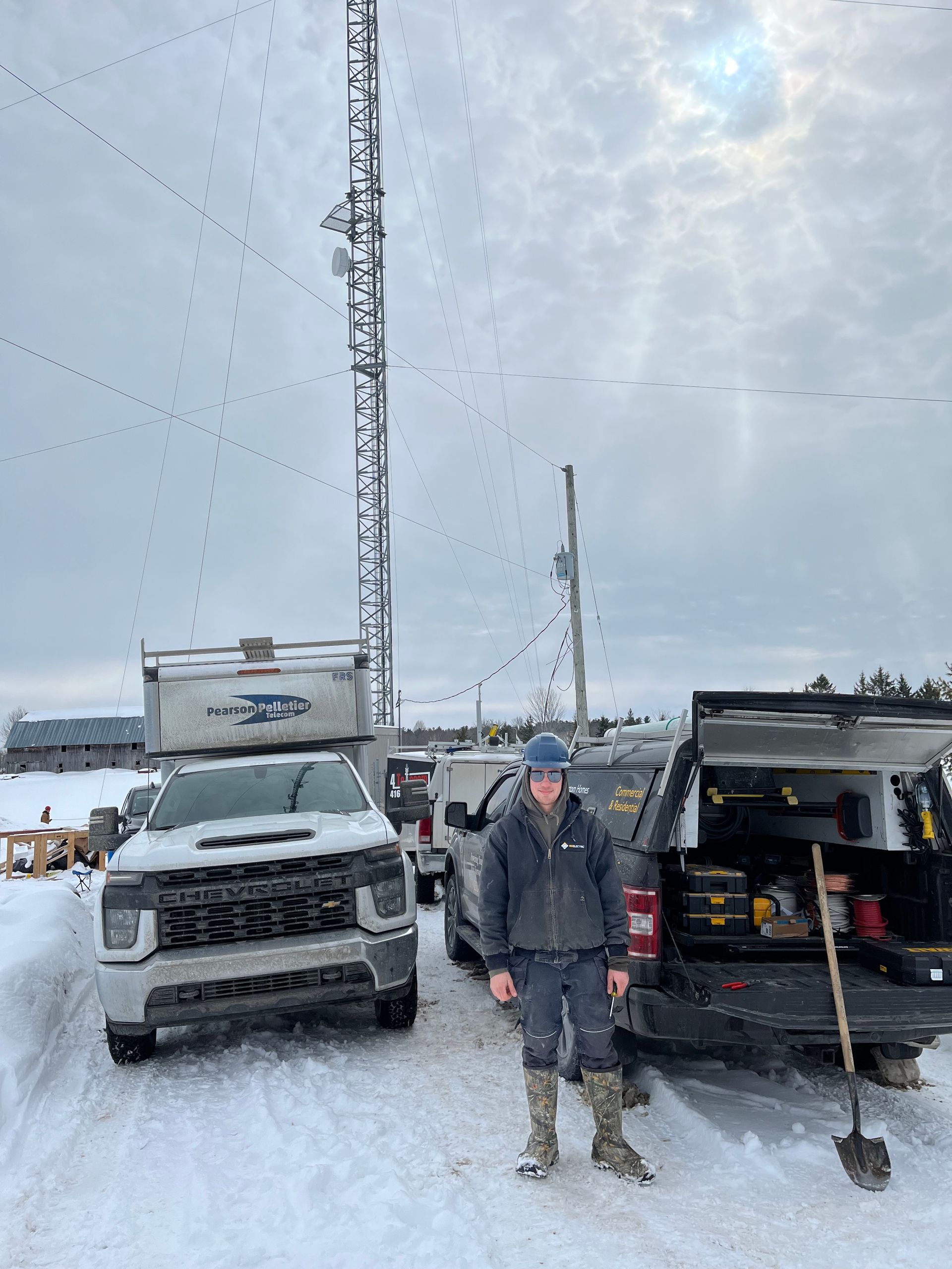 A man is standing in front of two trucks in the snow.