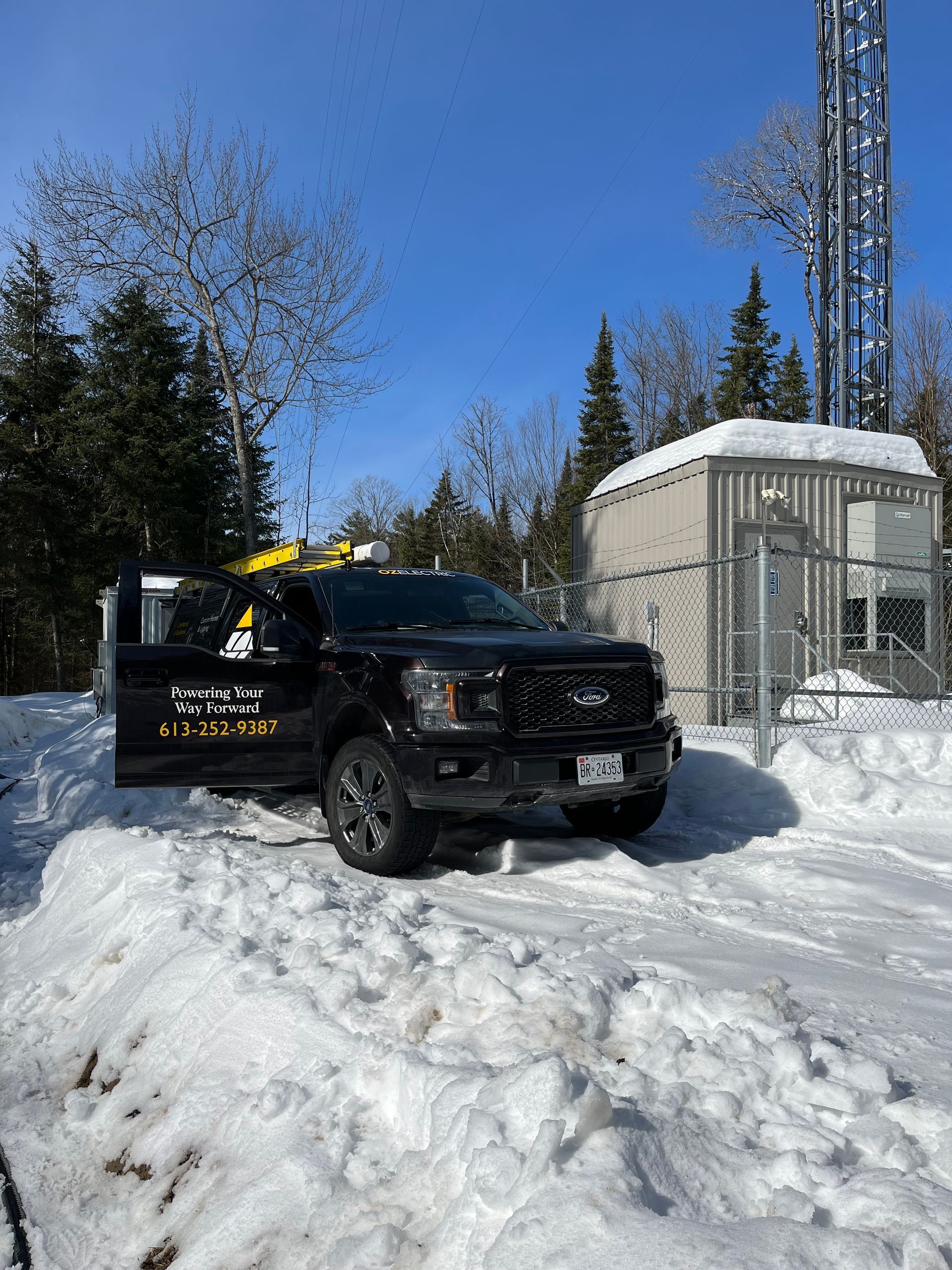 A black truck is parked in the snow in front of a building.
