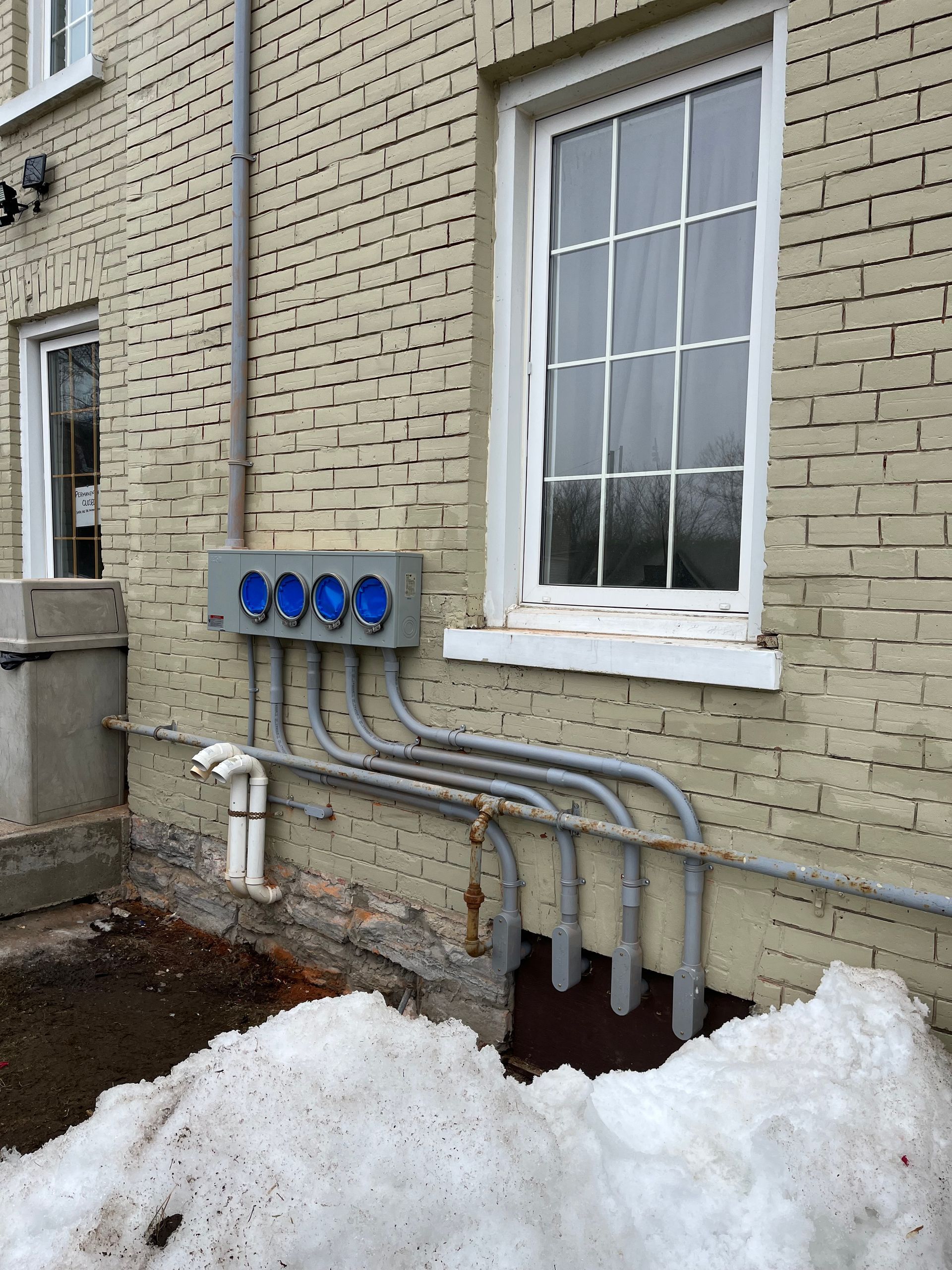 A brick building with a window and a bunch of wires coming out of it