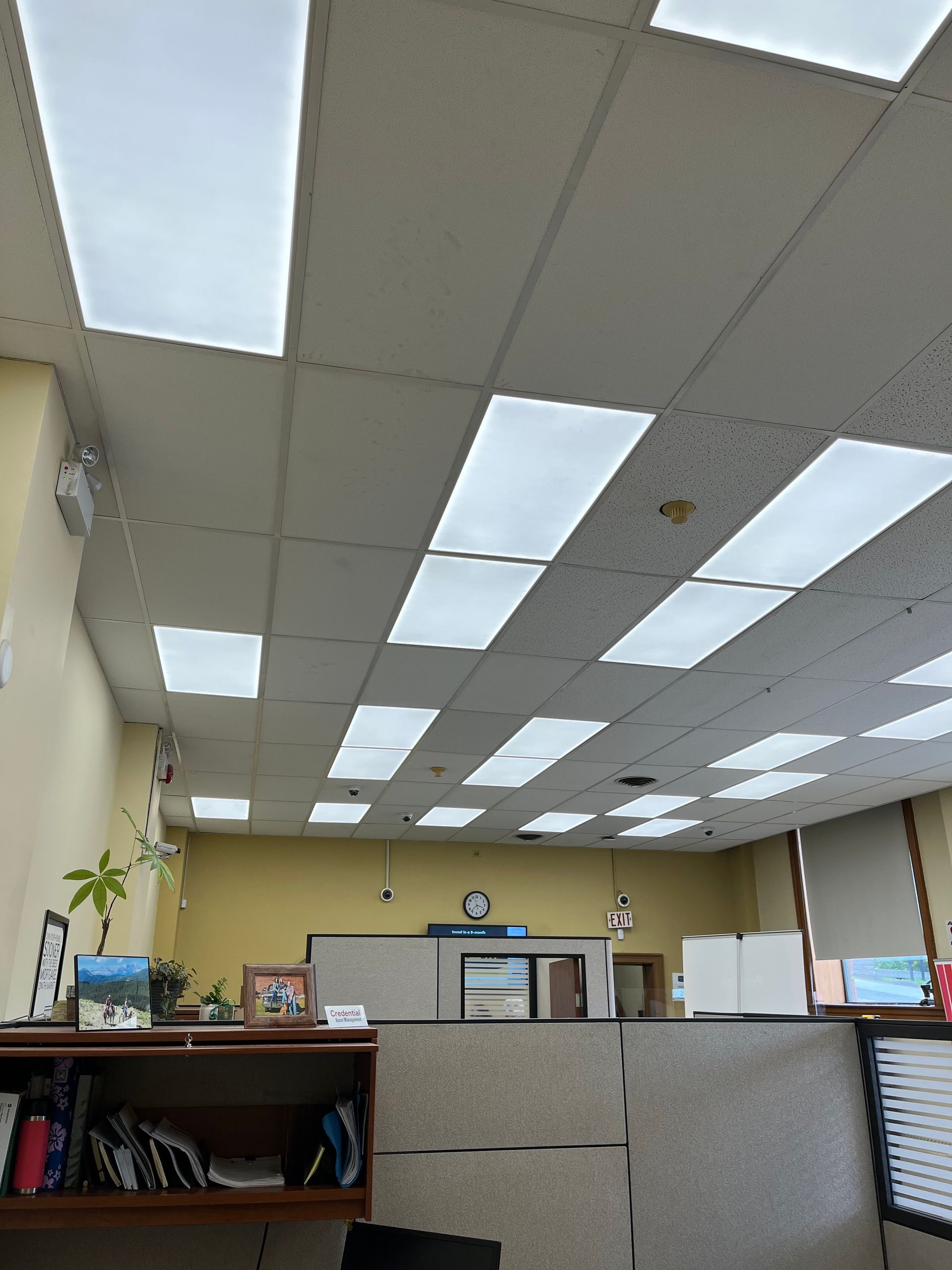 A cubicle in an office with a lot of lights on the ceiling