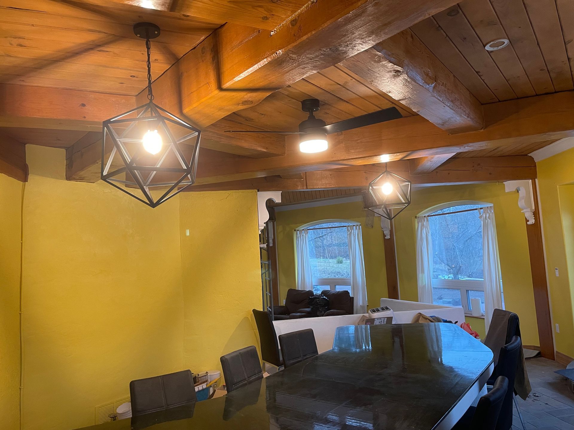 A dining room with a table and chairs and a wooden ceiling.