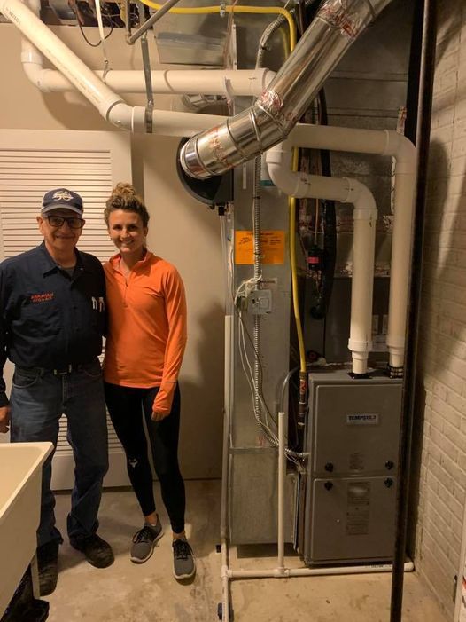 a man and a woman are standing next to a furnace in a basement .